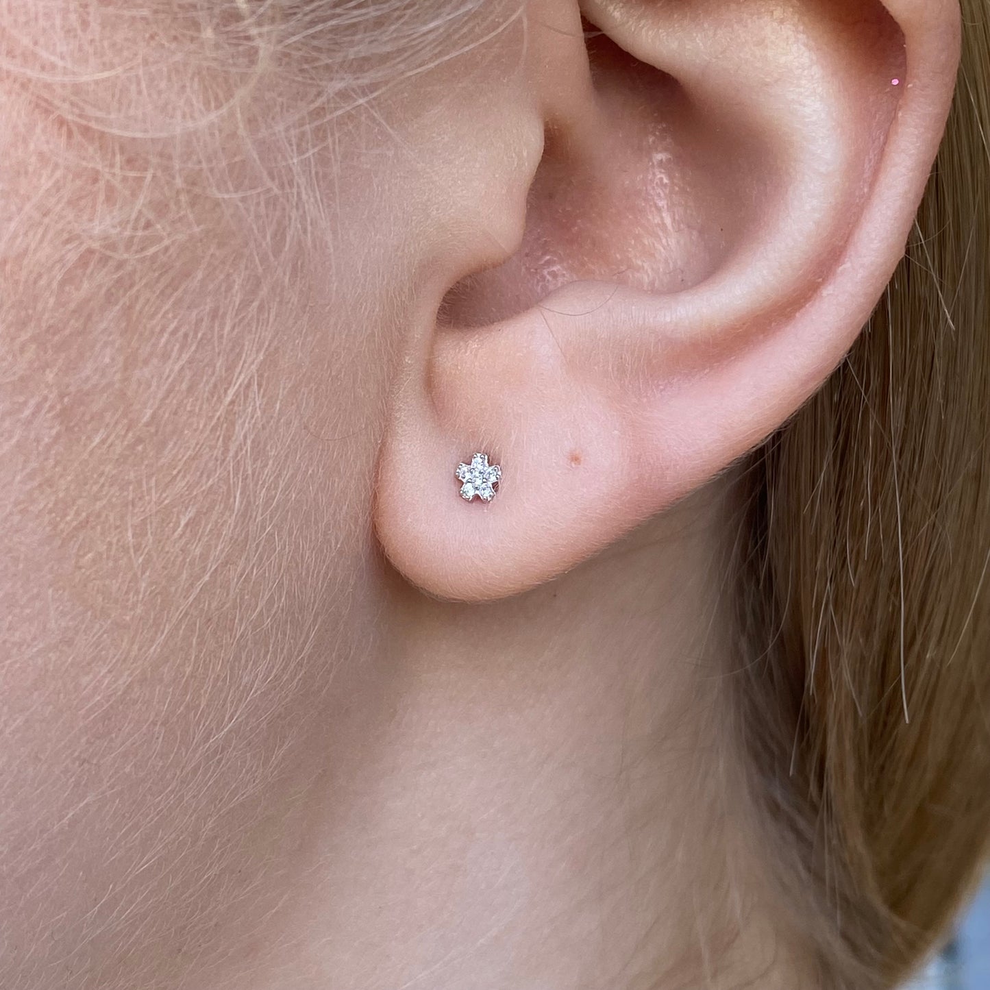 Kid's silver CZ flower stud earrings by Comero featuring sparkling cubic zirconia with a delicate floral design.