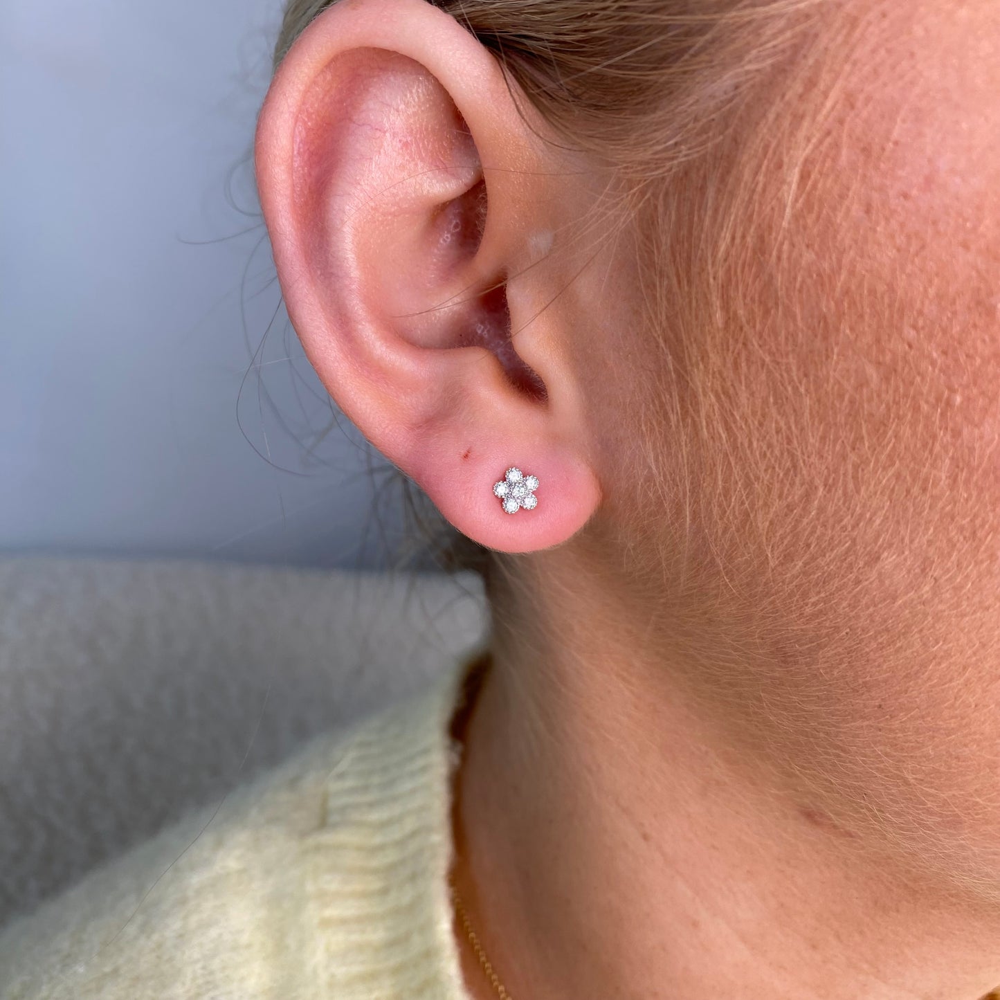 Silver CZ flower stud earrings for kids by Comero featuring sparkling cubic zirconia in a floral design.