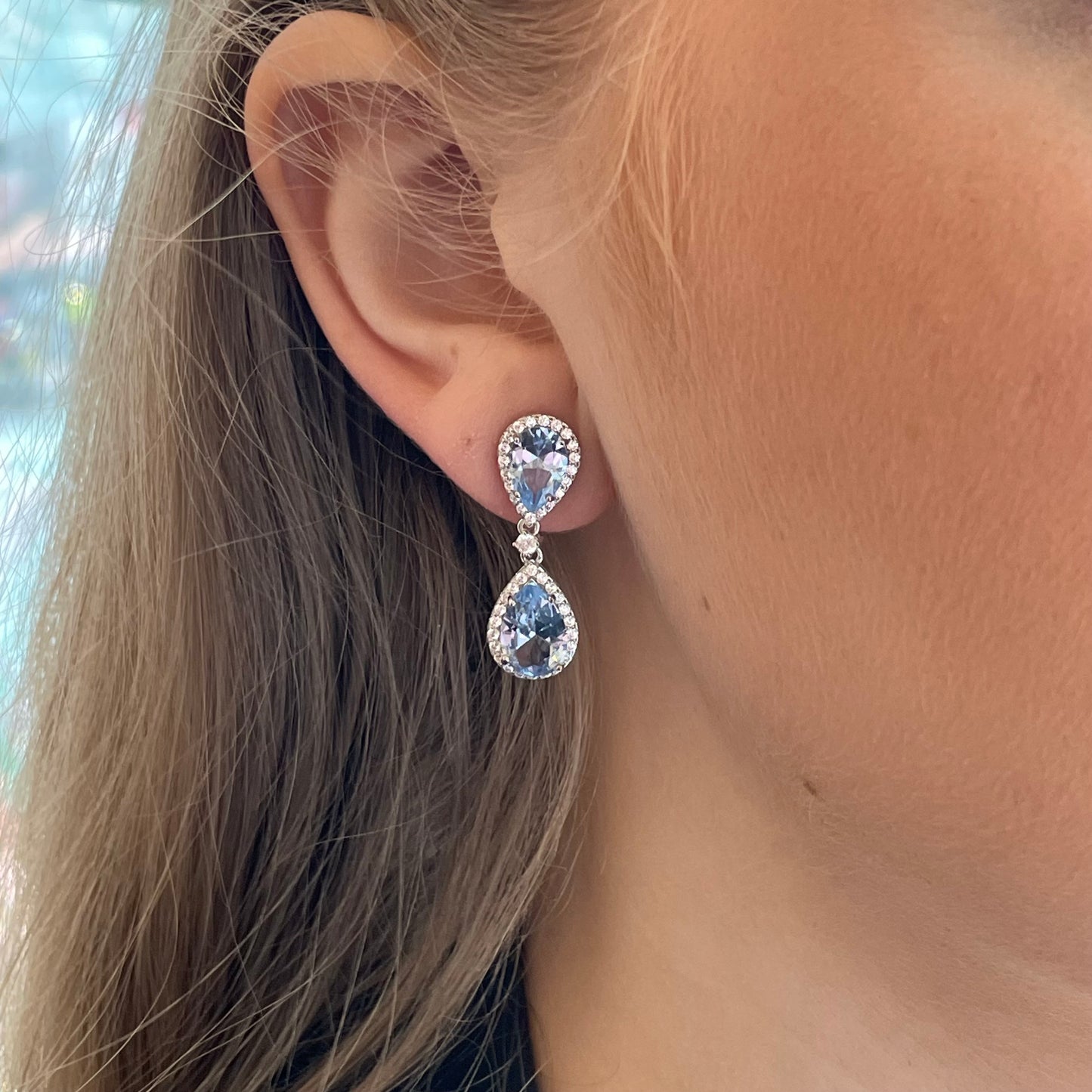 Silver Aqua Pear CZ Drop Earrings by Comero featuring teardrop-shaped aqua-blue cubic zirconia gemstones.