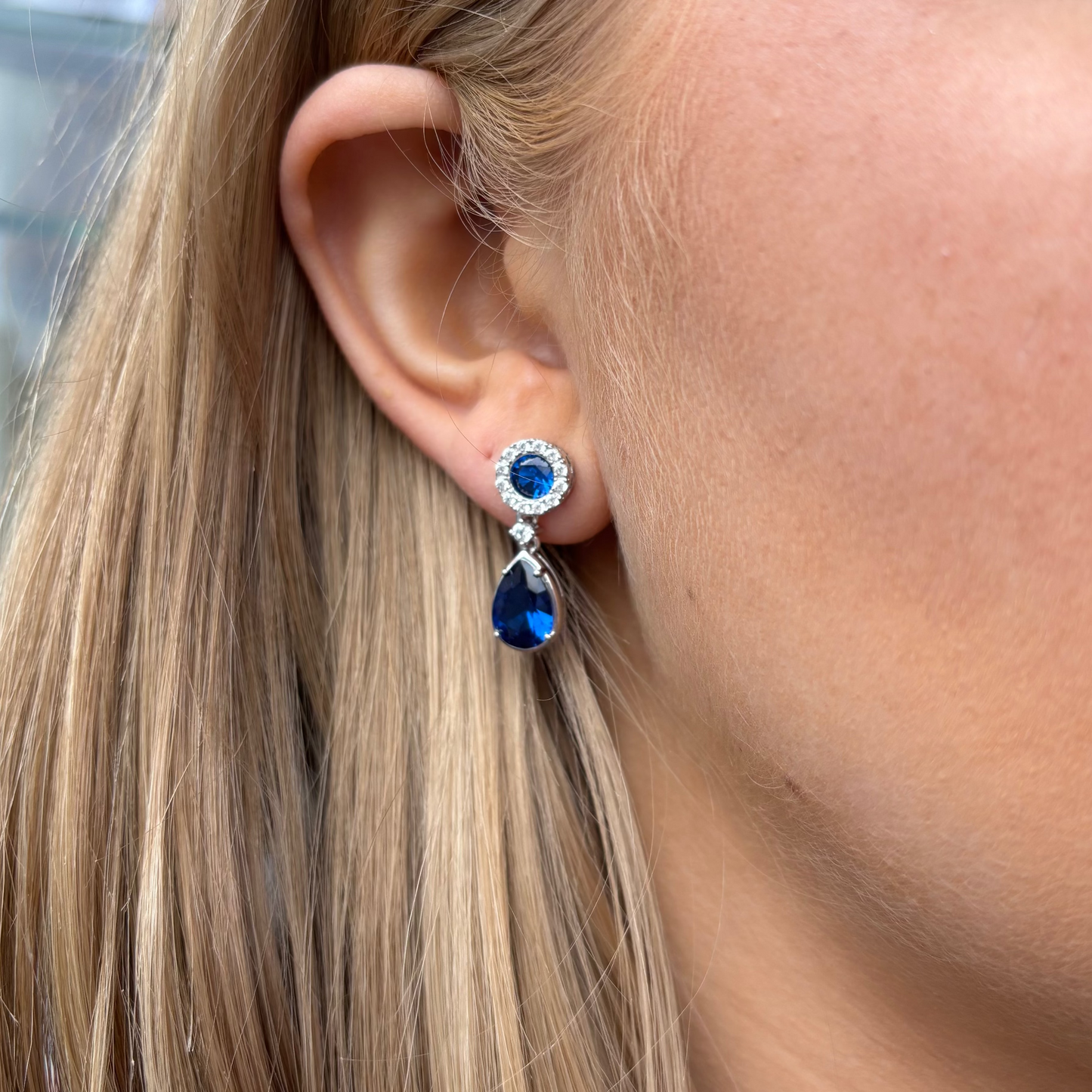 Silver sapphire blue pear-shaped CZ drop earrings by Comero featuring sparkling blue gemstone accents and elegant dangle design.