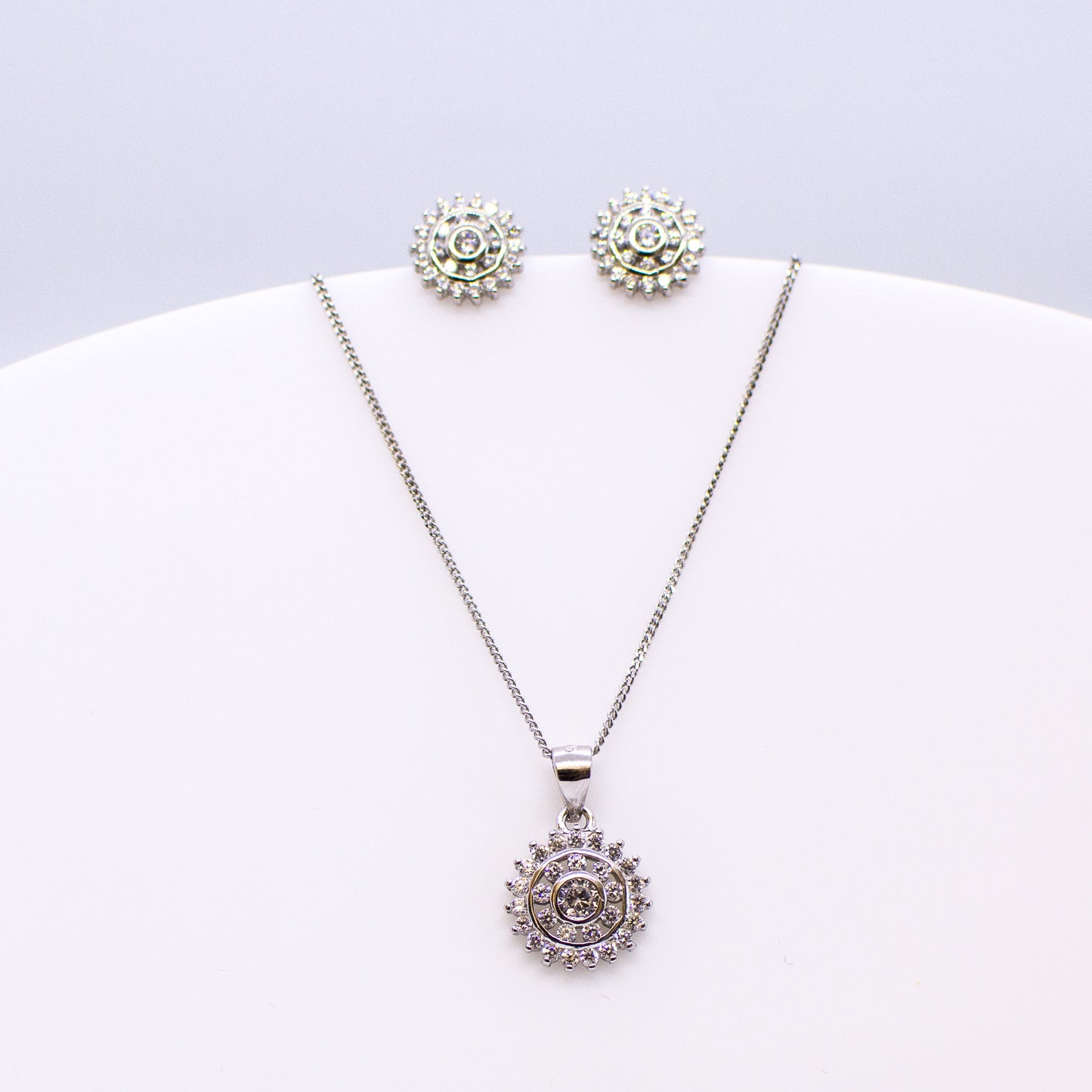 These sterling silver double halo stud earrings set with glittering cubic zirconia stones accompanied by the matching necklace are the perfect addition to any outfit. Product details: Product materials: 925 sterling silver, cubic zirconia Pendant dimensions: 14mm L x 12mm W Chain length: 44cm fine diamond cut curb chain Earring dimensions: 10mm W Stud earrings with butterfly backs.