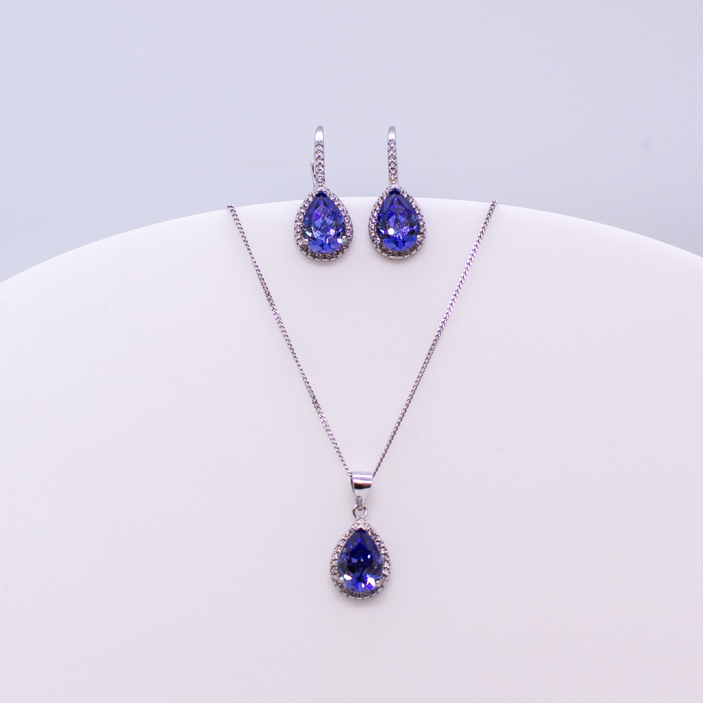 These sterling silver pear shaped drop earrings set with glittering cubic zirconia stones in created Tanzanite and white accompanied by the matching necklace are the perfect addition to any outfit. Product details: Product materials: 925 sterling silver, cubic zirconia Chain length: 44cm inch fine diamond cut curb chain Pendant dimensions: 20mm L x 10mm W Earring dimensions: 24mm L x 10mm W Drop earrings with integrated CZ set German wires.