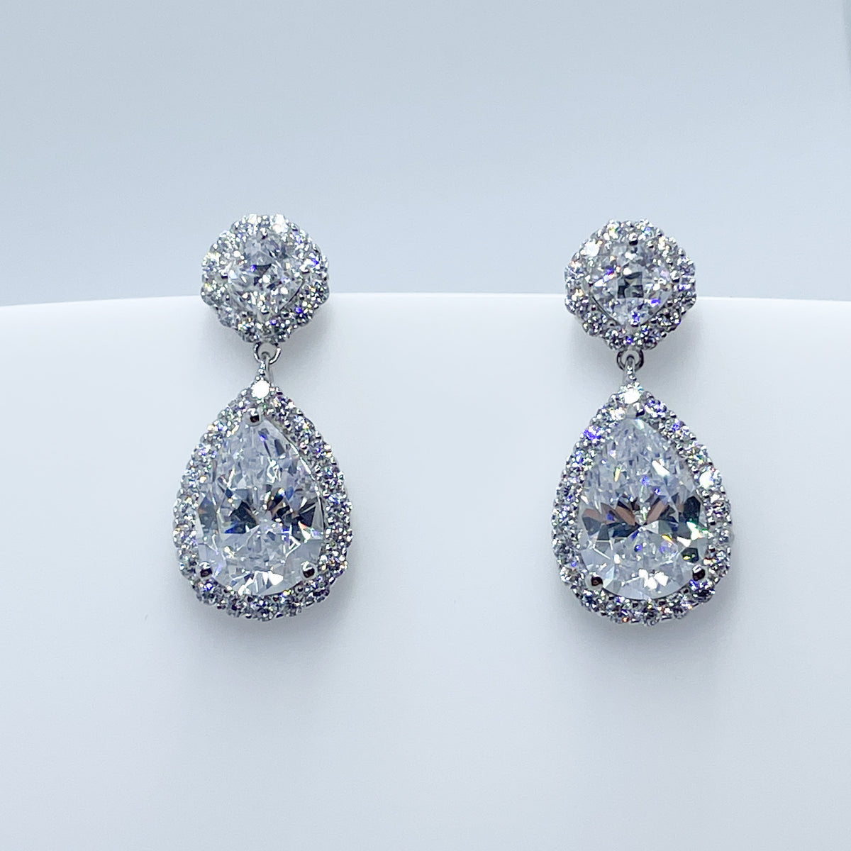 Silver Pear Cut CZ Halo Drop Earrings by Insignia featuring pear-shaped cubic zirconia with halo setting and drop design