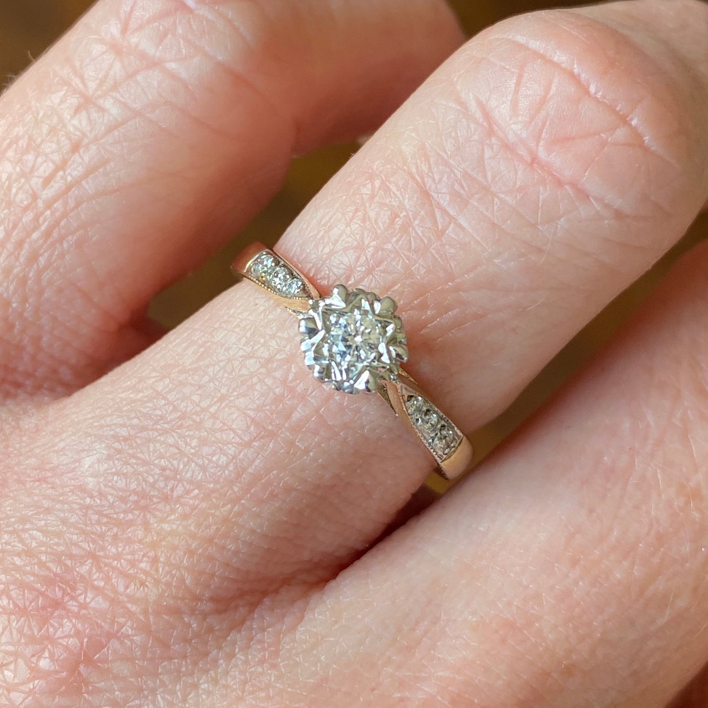 This solitaire diamond engagement ring is a complete classic. Its simplicity is so romantic. The Details... One 9ct gold diamond engagement ring. Round brilliant cut diamond with subtle star motif. 0.12ct Colour H. Clarity SI Diamond set tapered shoulders. 9ct yellow gold. Size N