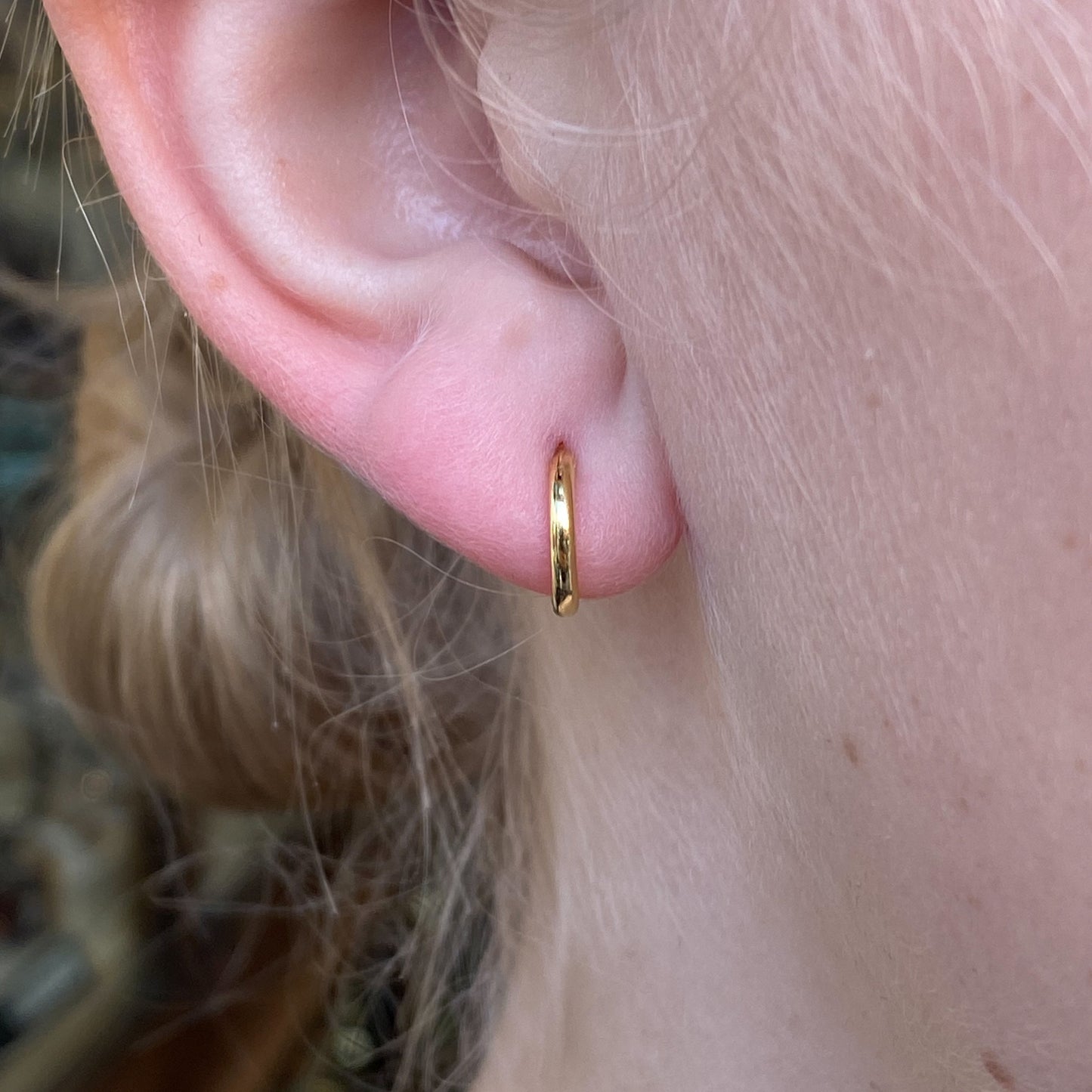 CME Sunshine Micro Huggie Hoop Earrings, 10mm, small gold earrings with a shiny finish, close-up of the jewelry on a white background
