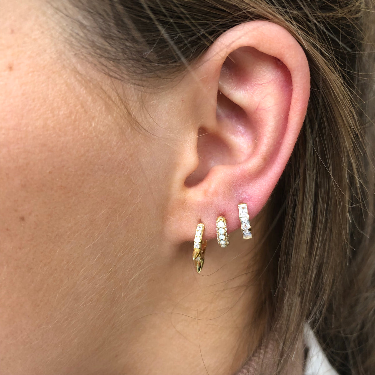 CME Sunshine Baguette Huggie Earrings featuring gold-tone hoops with baguette-cut gemstone accents.