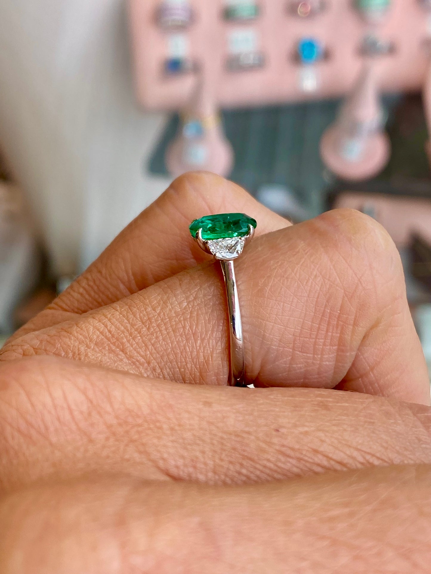 Herbert platinum emerald and diamond ring featuring a central emerald gemstone surrounded by sparkling diamonds.