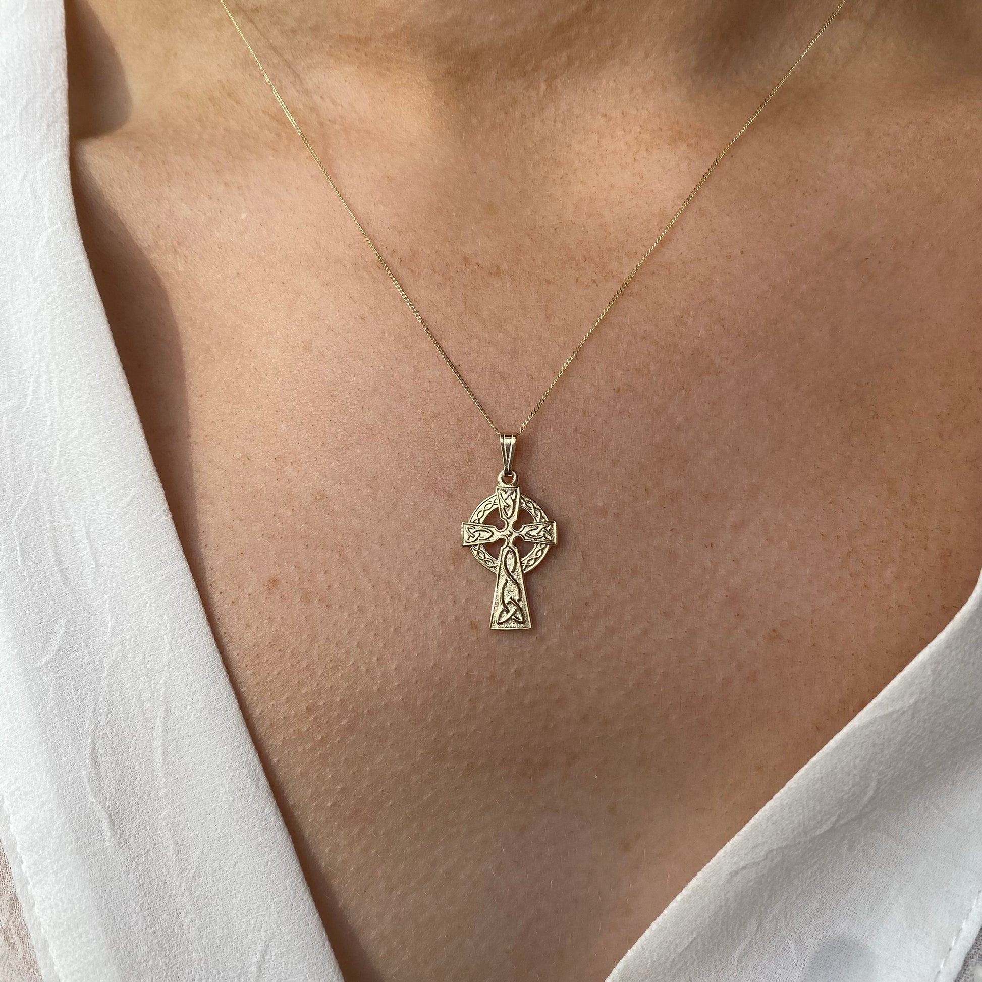 Facet 10ct gold Celtic cross necklace with detailed design, hanging on a chain, showcasing elegant jewelry craftsmanship.