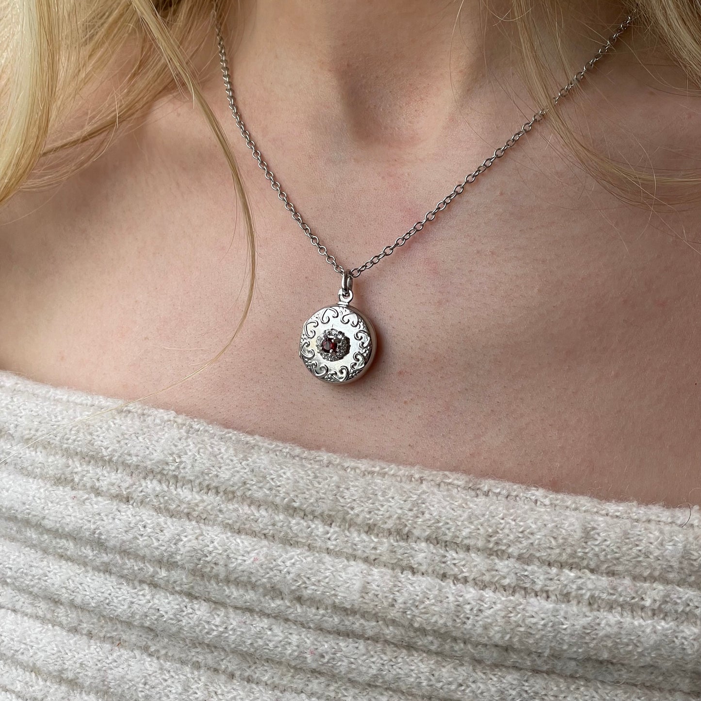 Silver round garnet and CZ embossed locket necklace with chain, featuring intricate design and polished finish.