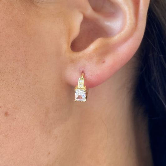Comero Sunshine CZ emerald cut huggie hoop earrings with sparkling gemstones and gold-tone finish, close-up view of earrings.