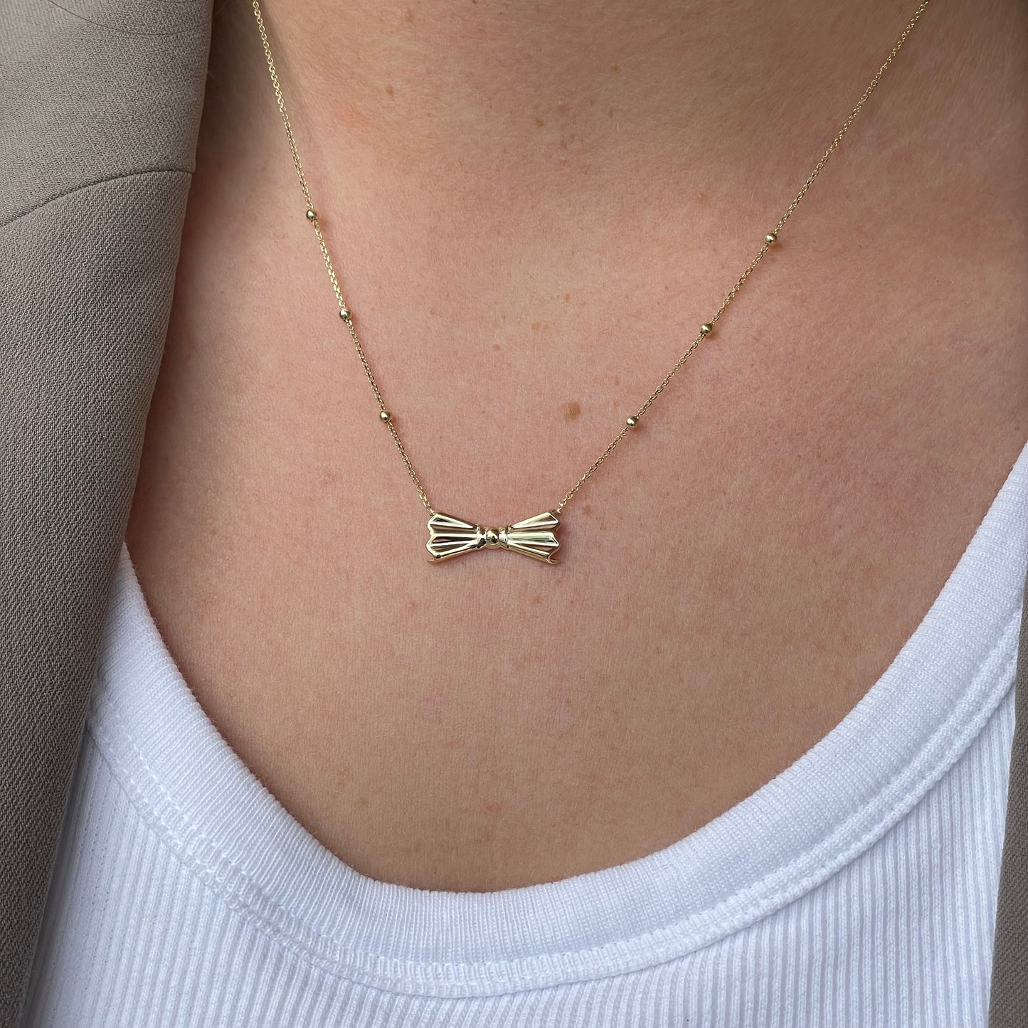 NJO 9ct gold bow and bead necklace with delicate chain and stylish design, featuring a charming bow pendant and bead accents.