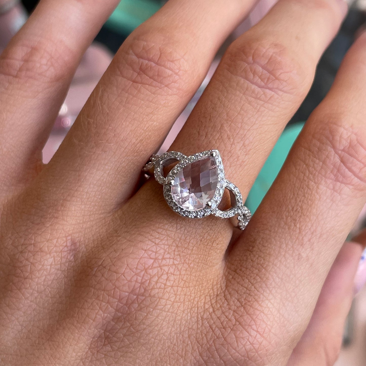 Silver Pear Halo Cluster Ring by Comero featuring a soft pink gemstone surrounded by a halo of silver, close-up of the elegant jewelry piece.