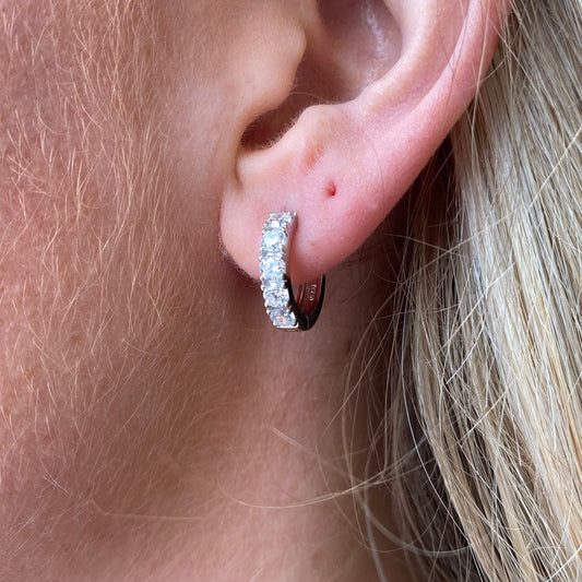 Silver CZ huggie hoop earrings by Comero featuring sparkling cubic zirconia stones and a sleek, modern hoop design.