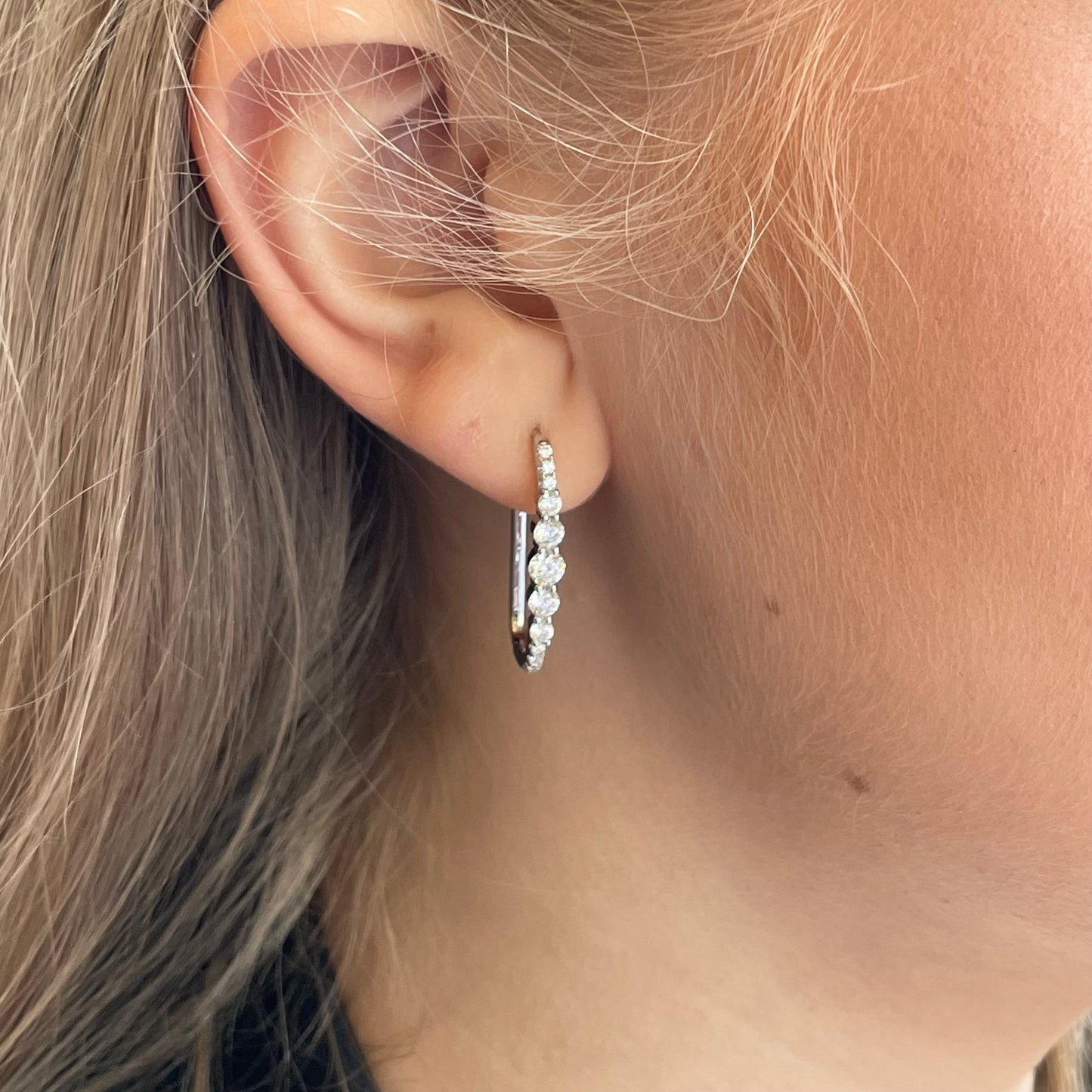 Silver elongated CZ huggie hoop earrings by Comero, featuring sparkling cubic zirconia stones and a sleek hoop design.