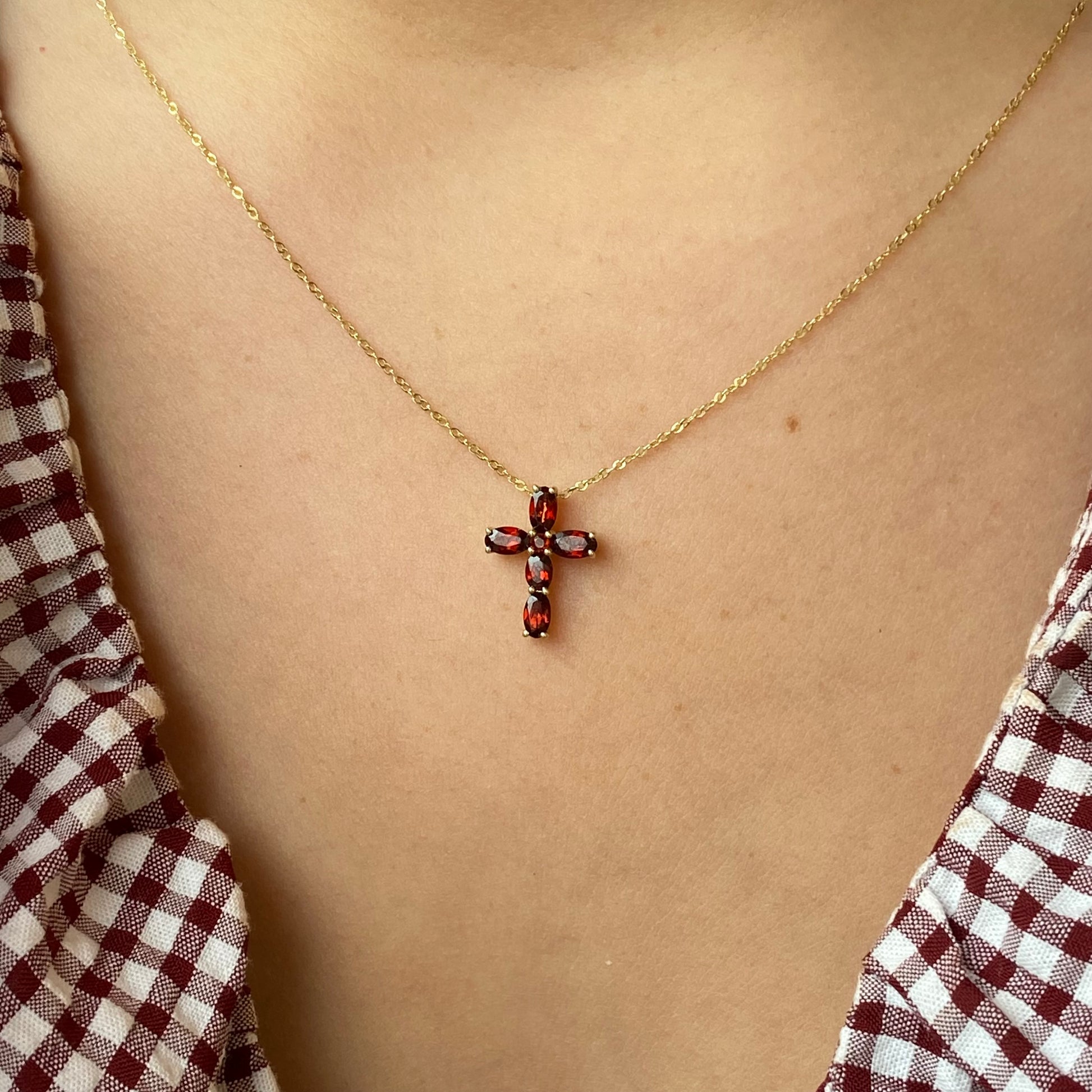 9ct gold garnet cross necklace with intricate design, featuring a vibrant red garnet gemstone on a delicate chain.