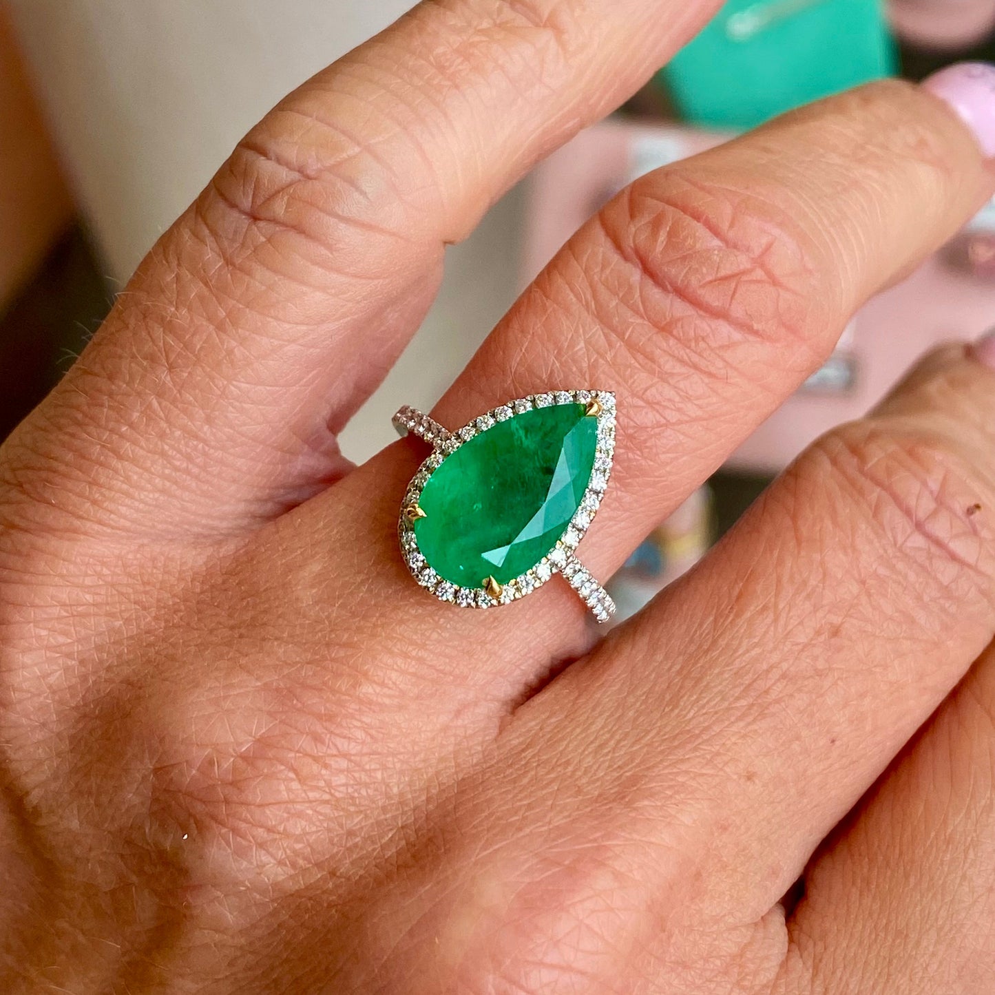 Herbert platinum emerald and diamond pear-shaped ring featuring a central emerald gemstone and sparkling diamonds set in platinum.