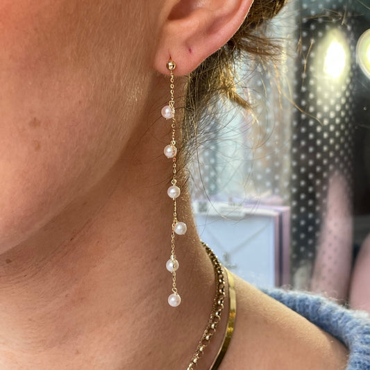 9ct gold freshwater pearl long drop earrings by Mark Milton, featuring elegant pearl strands hanging from gold hooks.