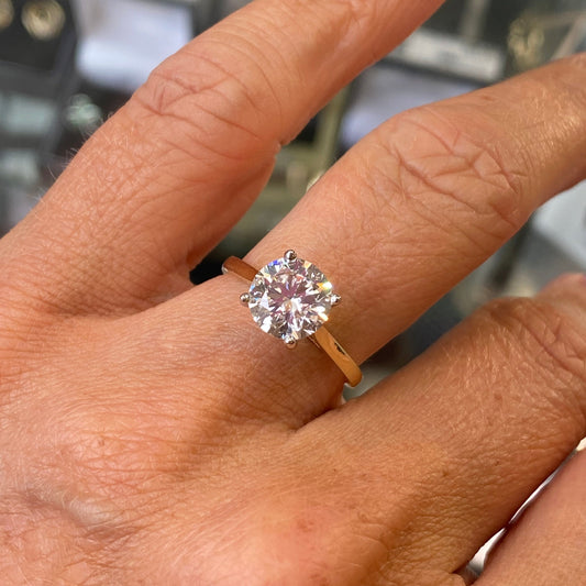 Gold ring with a diamond on a person's finger against a blurred background