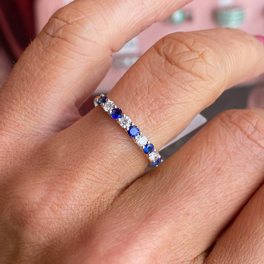 Close-up of a hand wearing an 18ct gold ring set with sapphires and diamonds.
