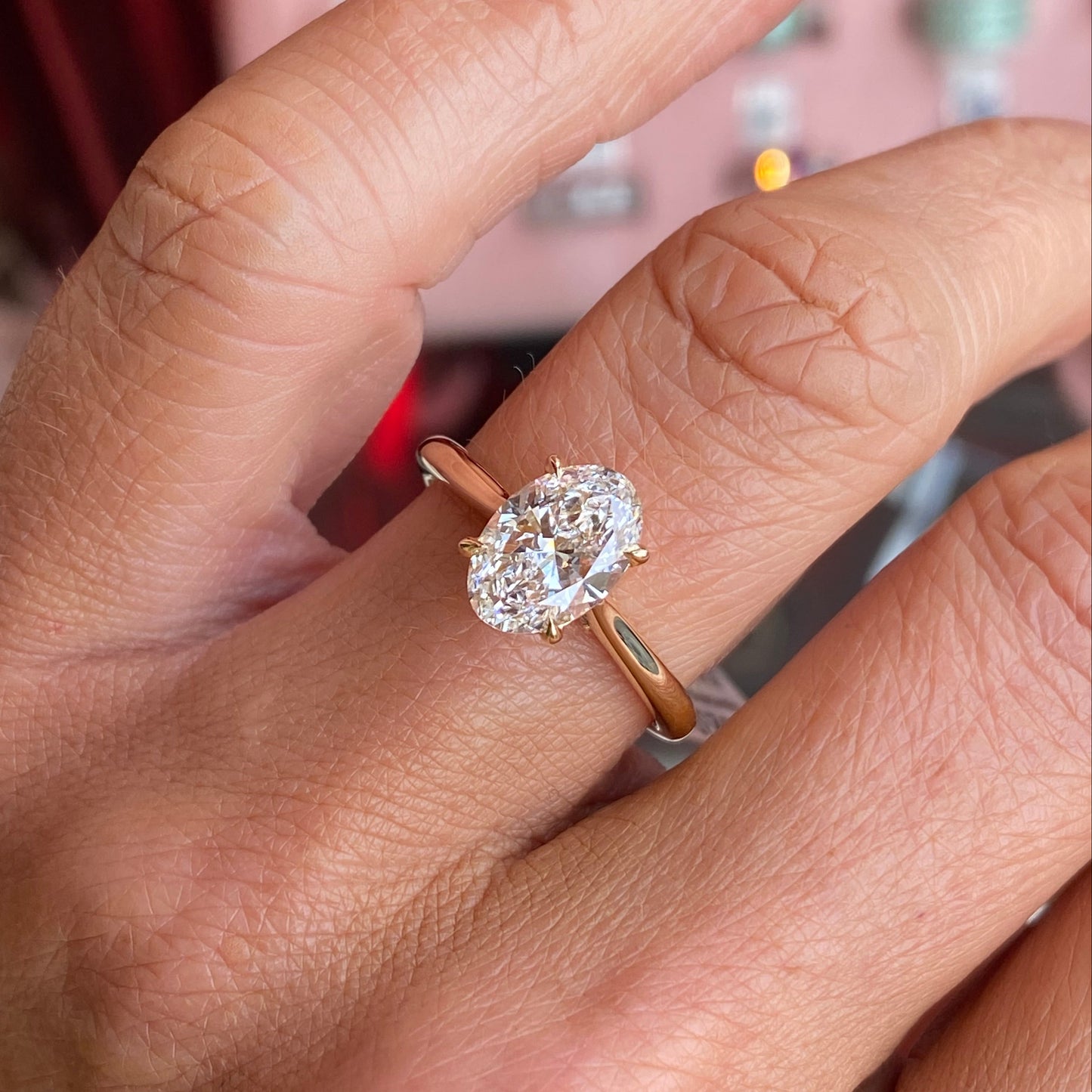 18ct yellow gold ring with a large oval cut lab diamond on a hand against a blurred background
