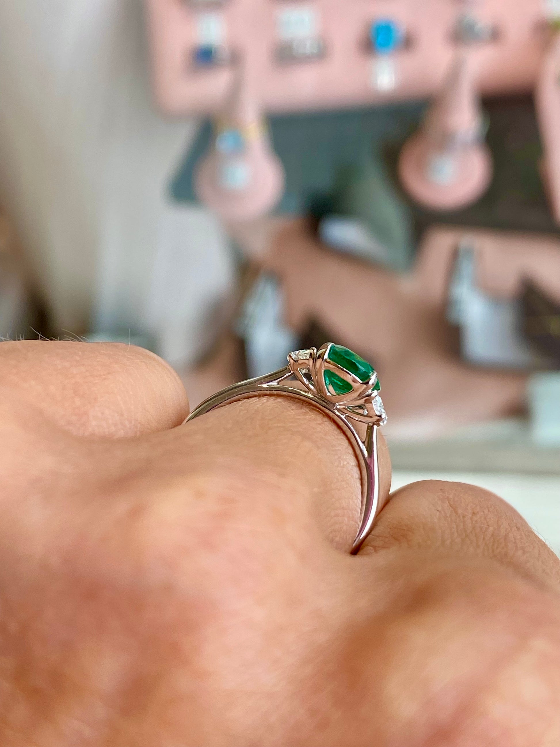 Herbert platinum ring featuring a central emerald gemstone surrounded by sparkling diamonds, elegant and luxurious jewelry piece.