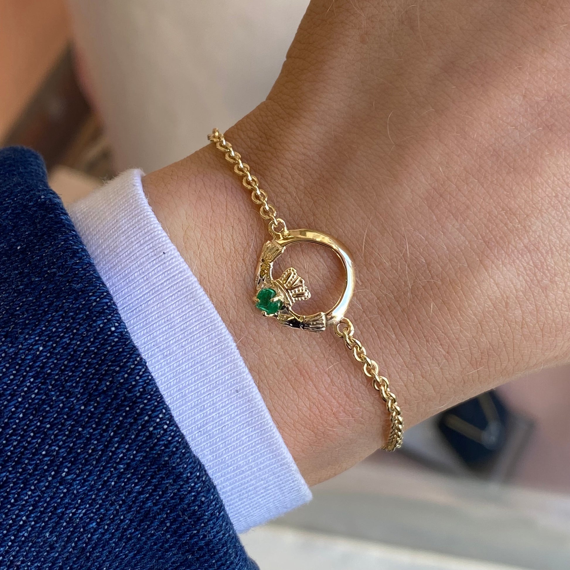 Facet 10ct gold Claddagh bracelet with green stone, featuring intricate Celtic design and delicate chain.