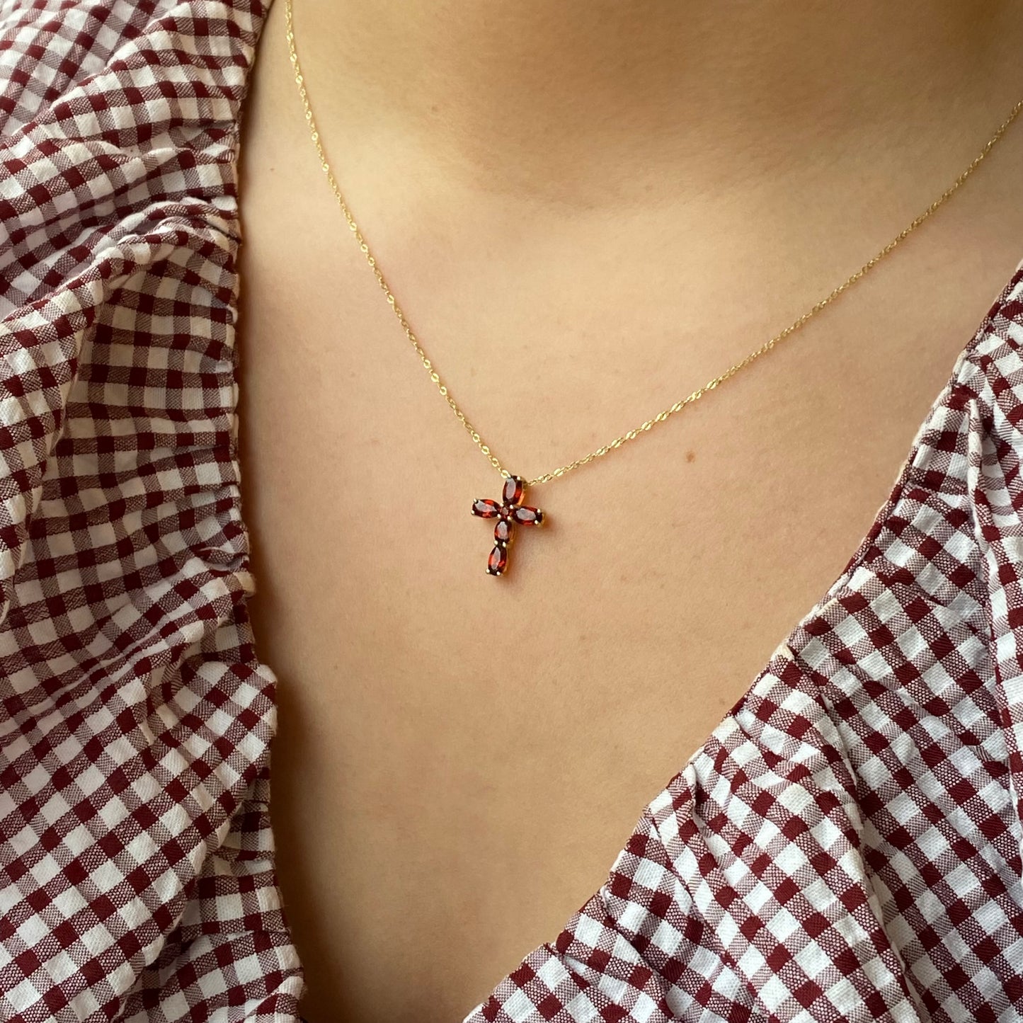 9ct gold garnet cross necklace featuring a detailed garnet gemstone pendant on a fine gold chain.