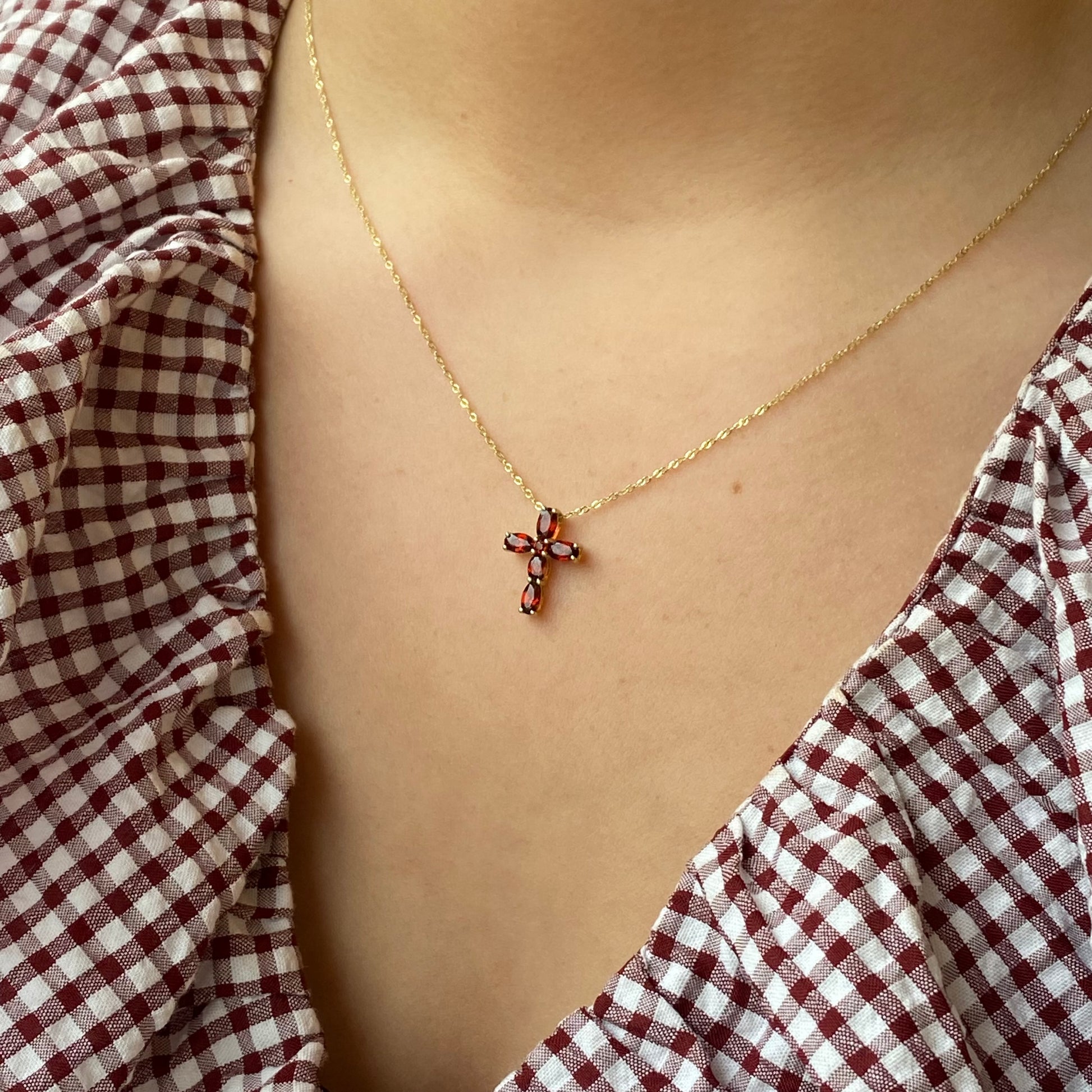 9ct gold garnet cross necklace featuring a detailed garnet gemstone pendant on a fine gold chain.