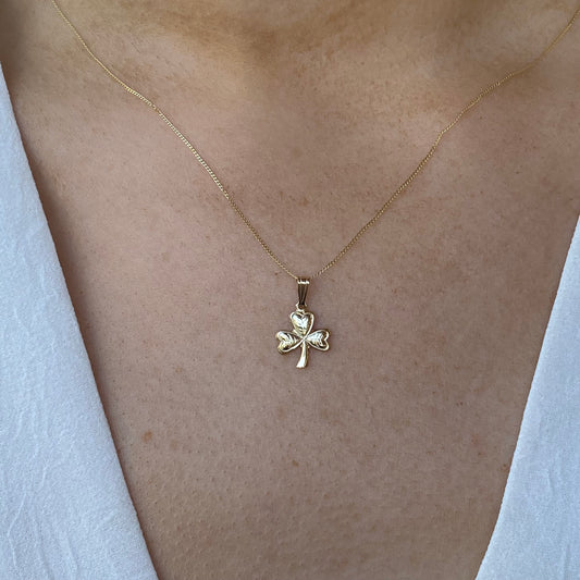 Mini gold shamrock necklace by Facet, featuring a delicate gold pendant in the shape of a shamrock.