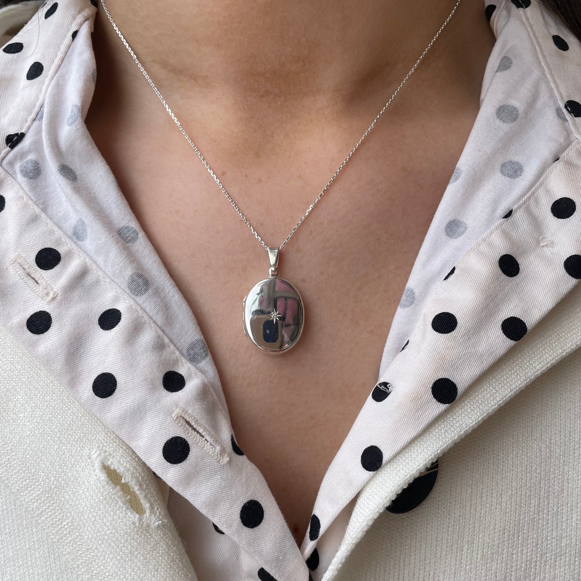 Silver diamond-set oval locket necklace by Clandela featuring a polished silver finish and intricate design.