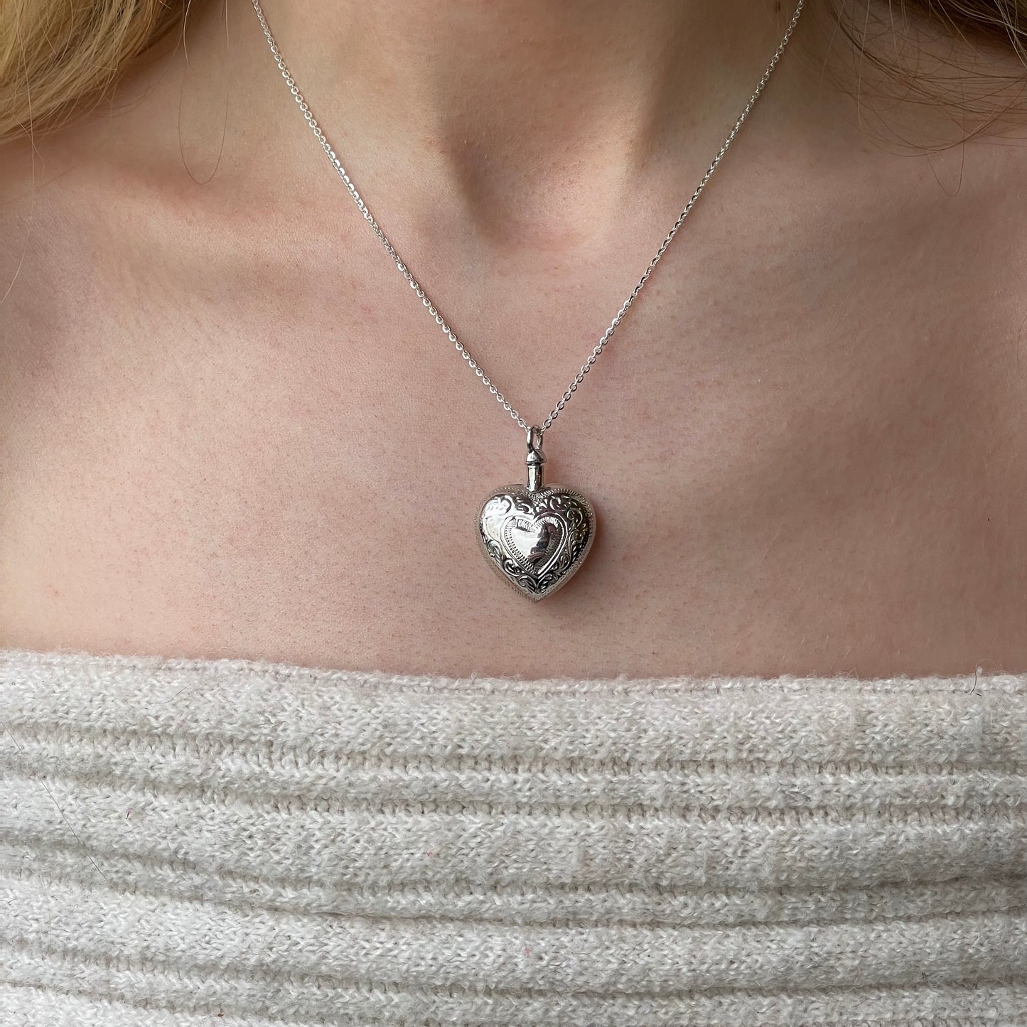 Silver engraved heart ash locket necklace with intricate designs, featuring a polished silver finish and a secure chain.