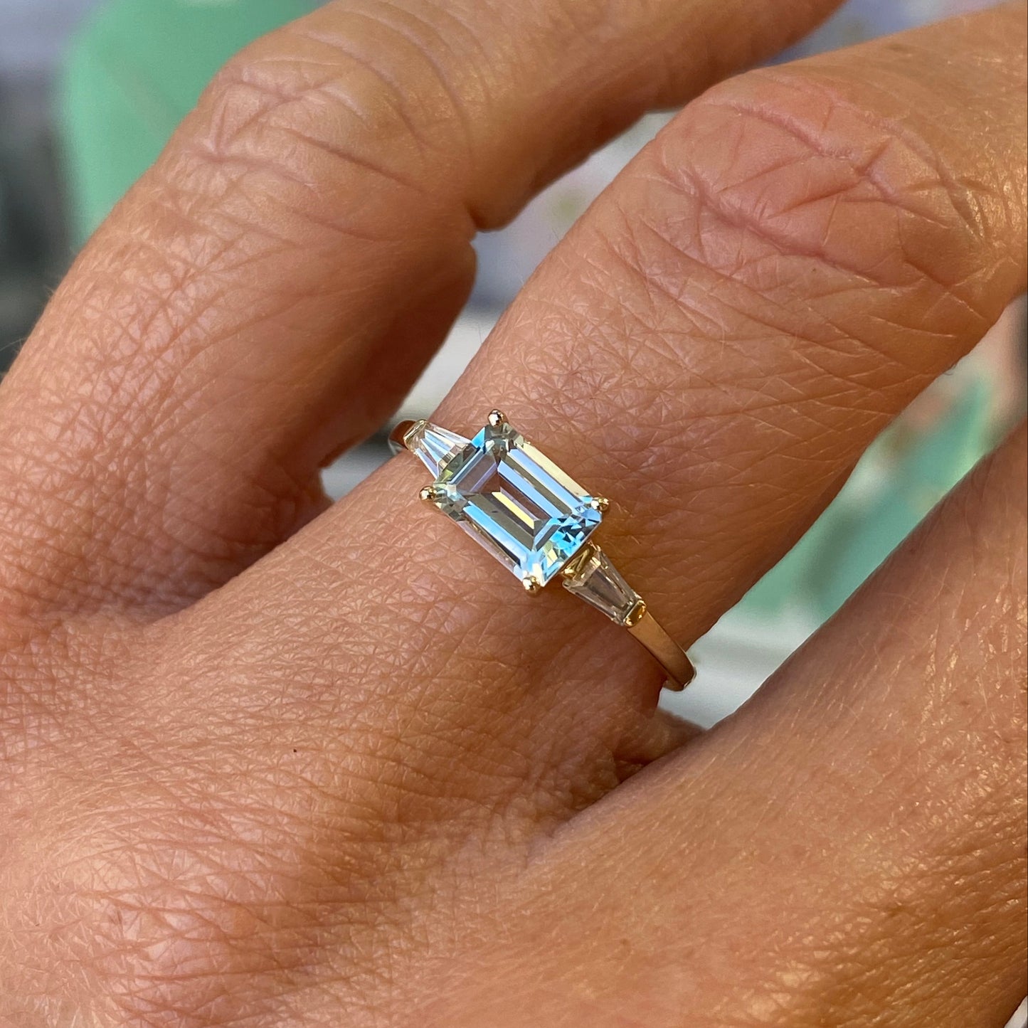 Insignia 9ct gold east west ring featuring a sky blue topaz and cubic zirconia accents on a polished gold band.