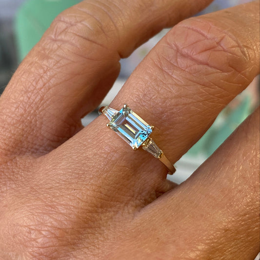 Insignia 9ct gold east west ring featuring a sky blue topaz and cubic zirconia accents on a polished gold band.