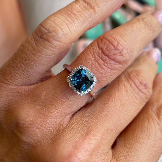 Herbert 9ct white gold cushion cut London Blue Topaz and diamond ring showcasing a blue gemstone surrounded by small diamonds.