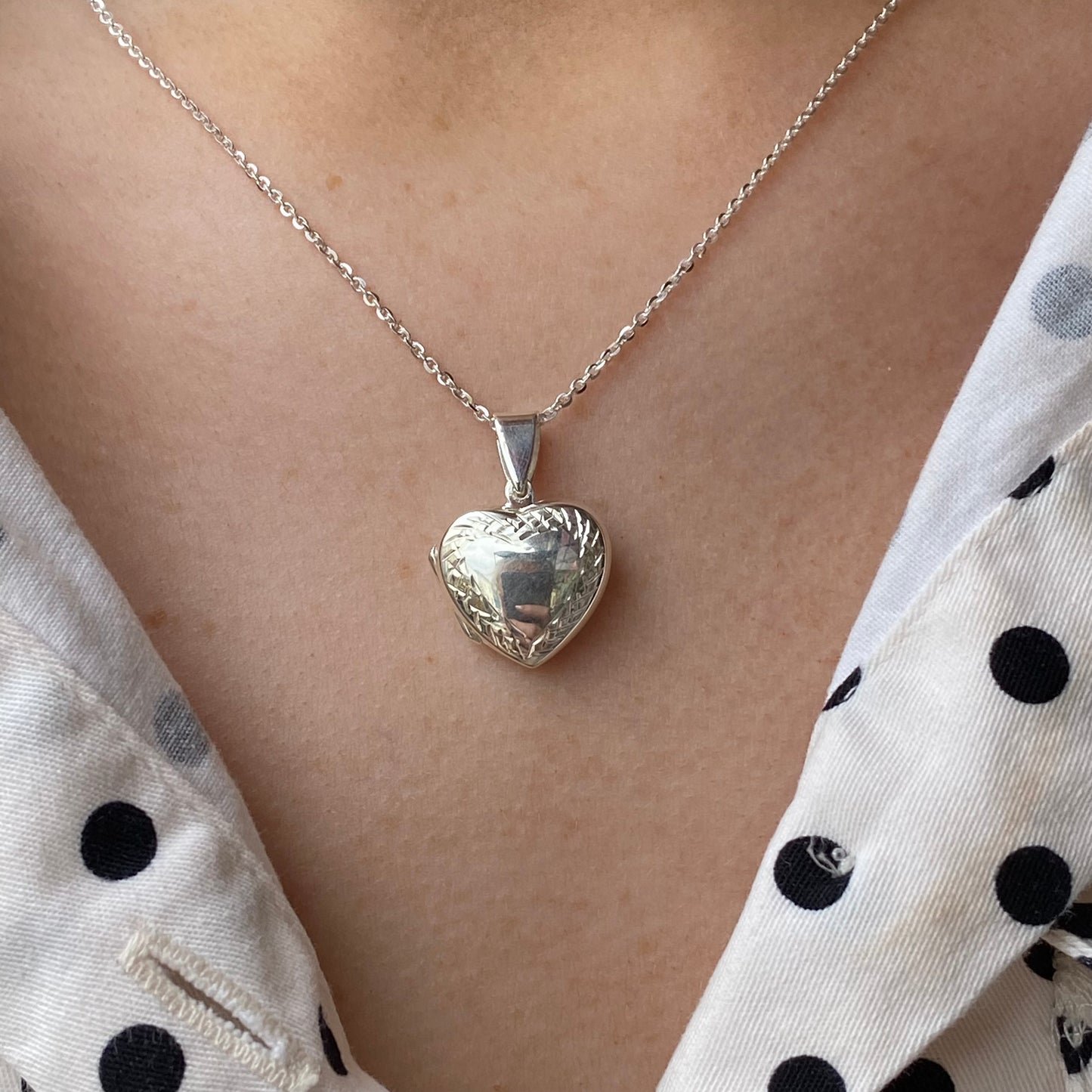 Silver diamond cut border heart locket necklace by THC, featuring a detailed heart-shaped pendant with intricate border design.