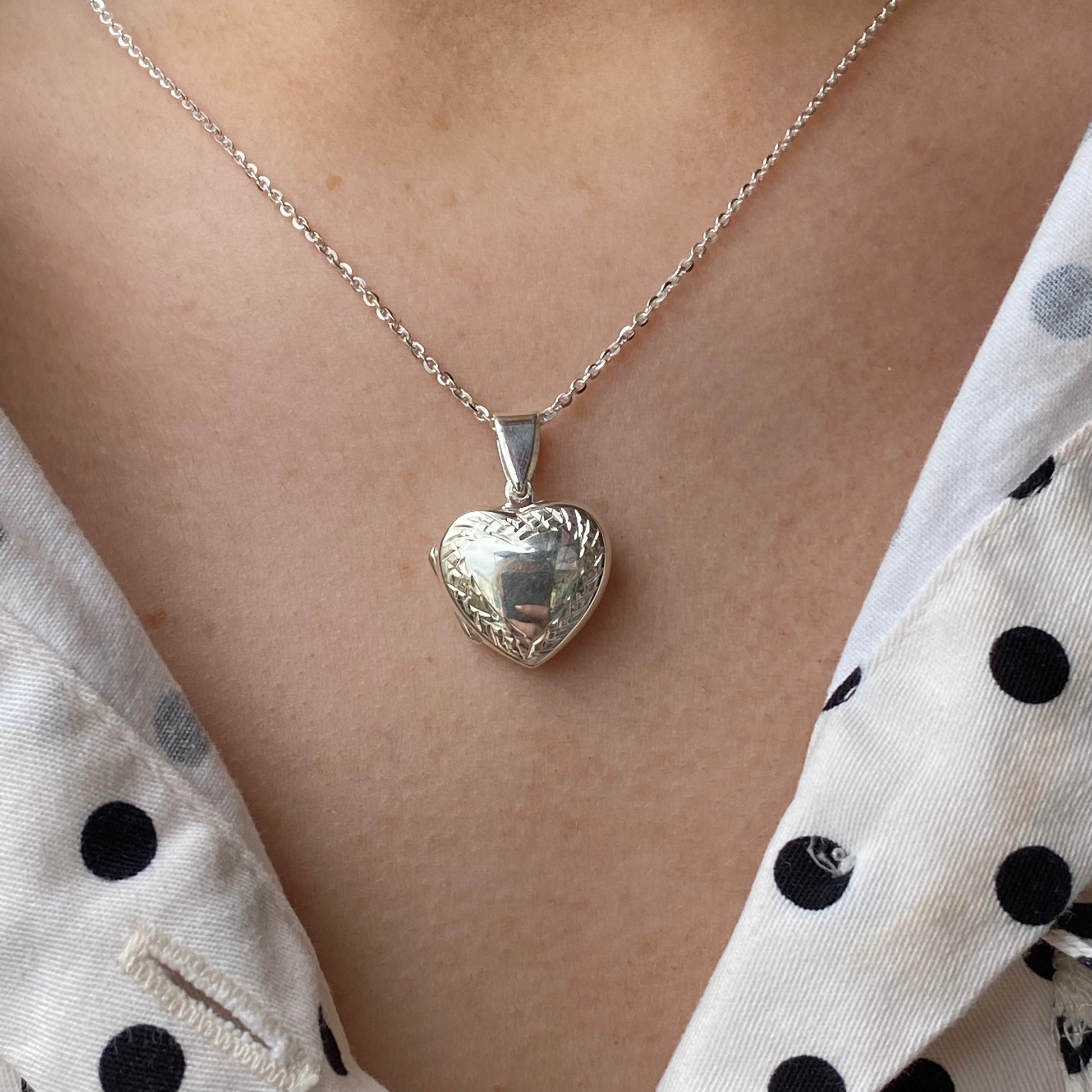 Silver diamond cut border heart locket necklace by THC, featuring a detailed heart-shaped pendant with intricate border design.