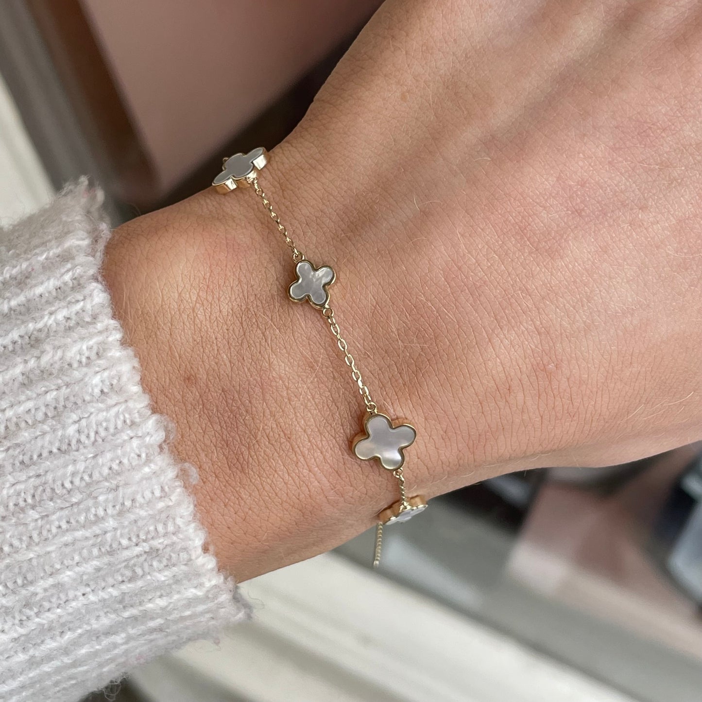 9ct gold mother of pearl graduated quatrefoil bracelet by Mark Milton, featuring elegant pearl-inlaid quatrefoil charms.
