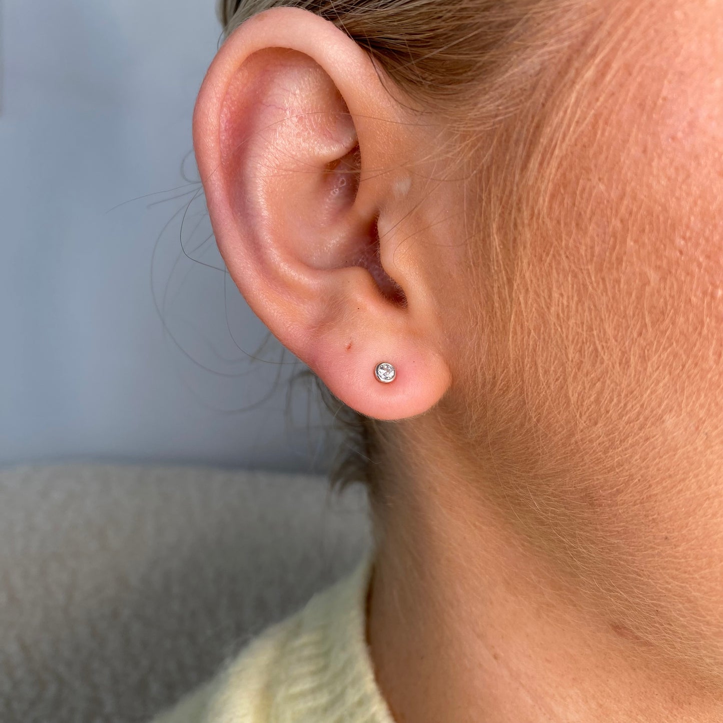 Silver 1.5mm CZ bezel set kid's stud earrings by Comero showing sparkling cubic zirconia stones on silver posts