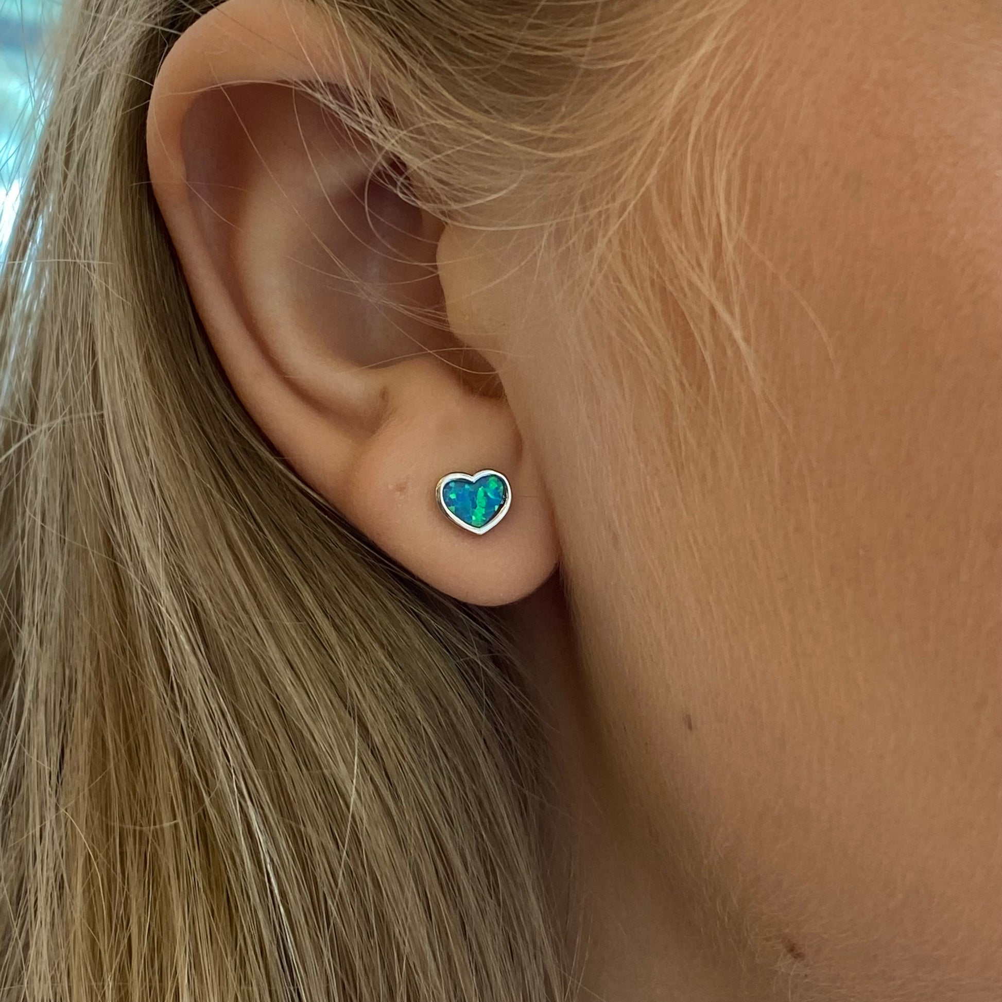 Silver blue opalique heart stud earrings by Insignia featuring shimmering gemstone accents and classic stud design.