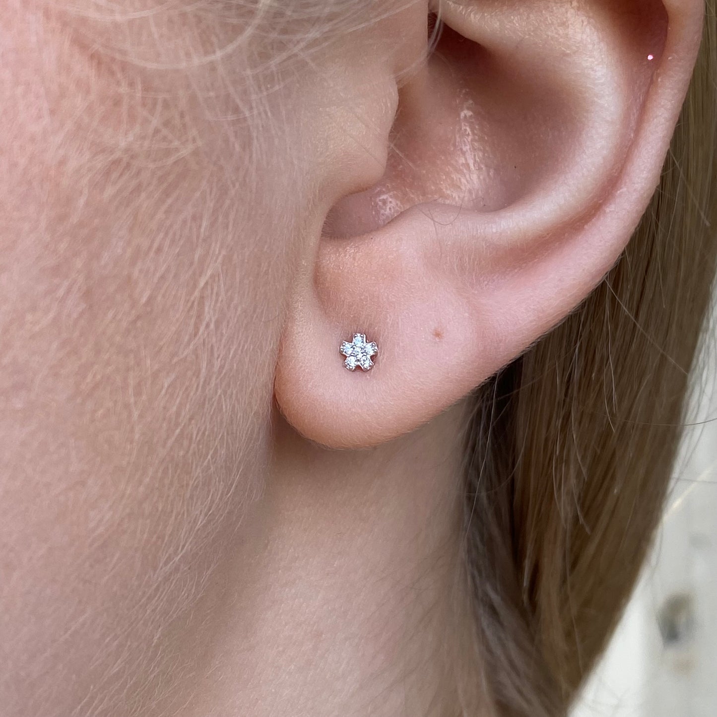 Silver CZ flower stud earrings for kids by Comero, featuring sparkling cubic zirconia in a delicate floral design.
