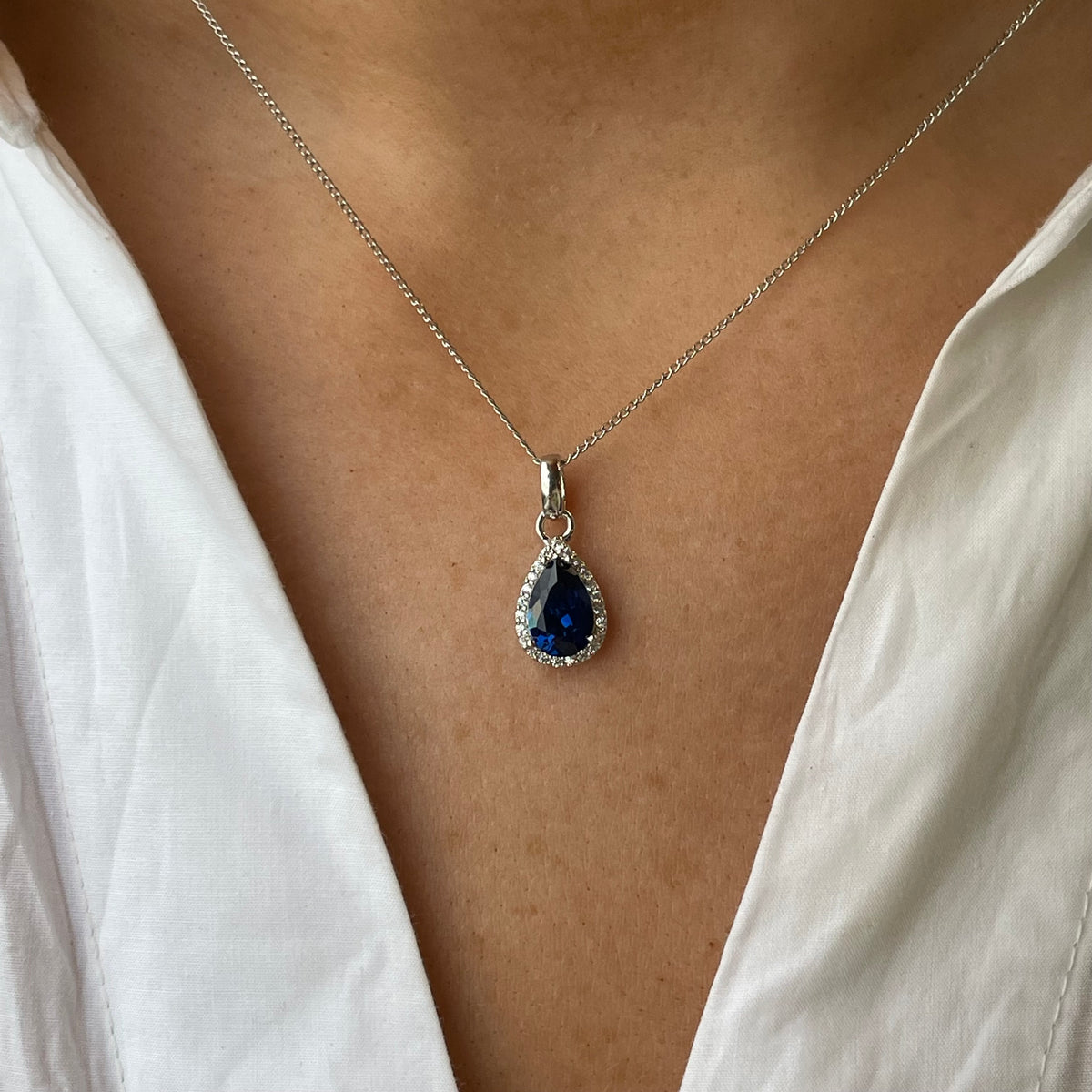 Silver created sapphire and CZ pear-shaped pendant necklace featuring a sparkling gemstone and elegant chain design.
