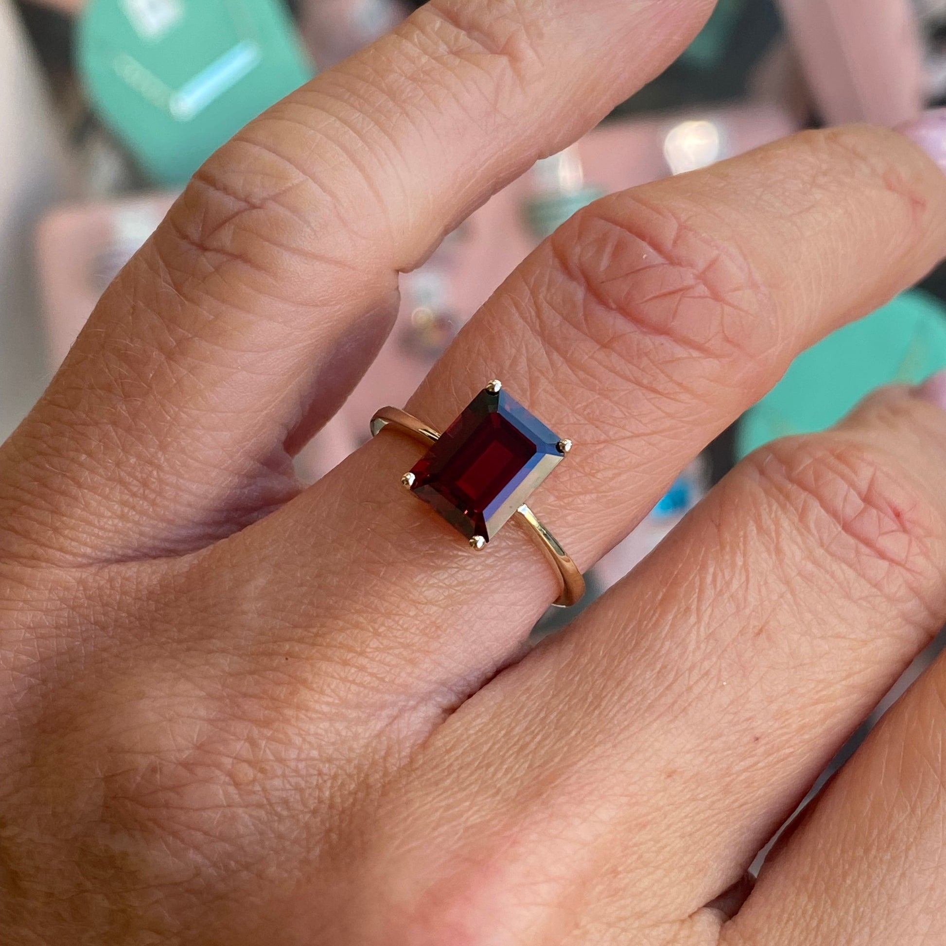 Insignia 9ct gold emerald cut garnet ring with a sleek band and polished finish, showcasing the vibrant gemstone.