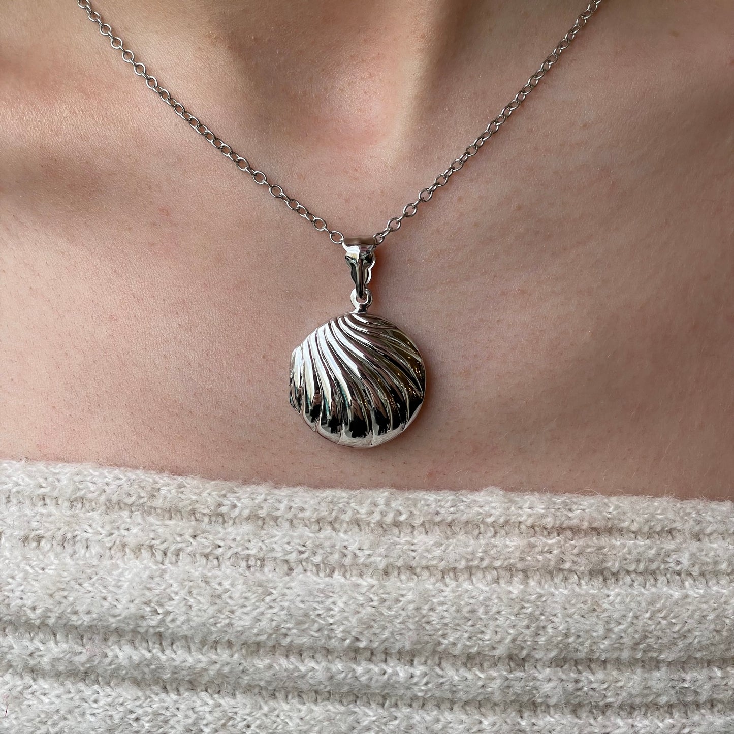 Silver round fluted locket necklace with chain, featuring a polished, decorative locket design on a delicate chain.