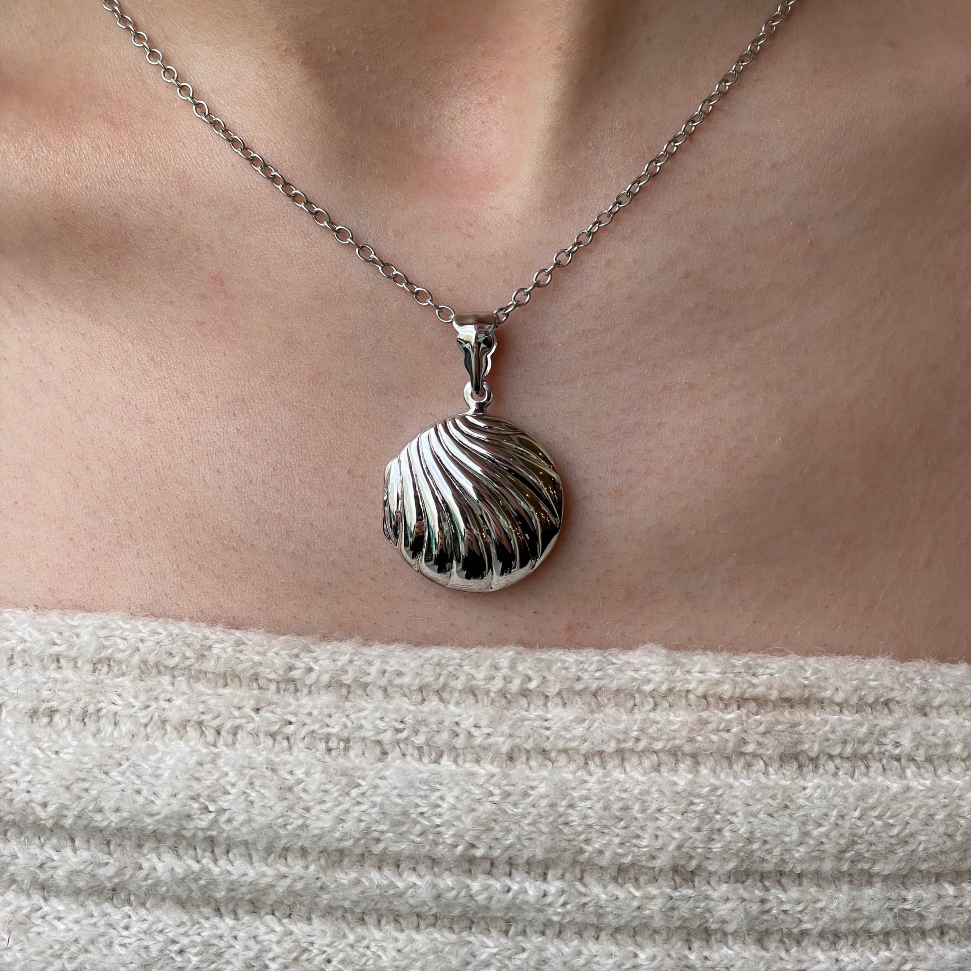 Silver round fluted locket necklace with chain, featuring a polished, decorative locket design on a delicate chain.