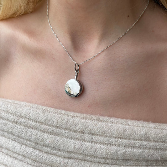 Silver round ash locket necklace by Insignia with a polished silver pendant and chain, showcasing a sleek, elegant design.