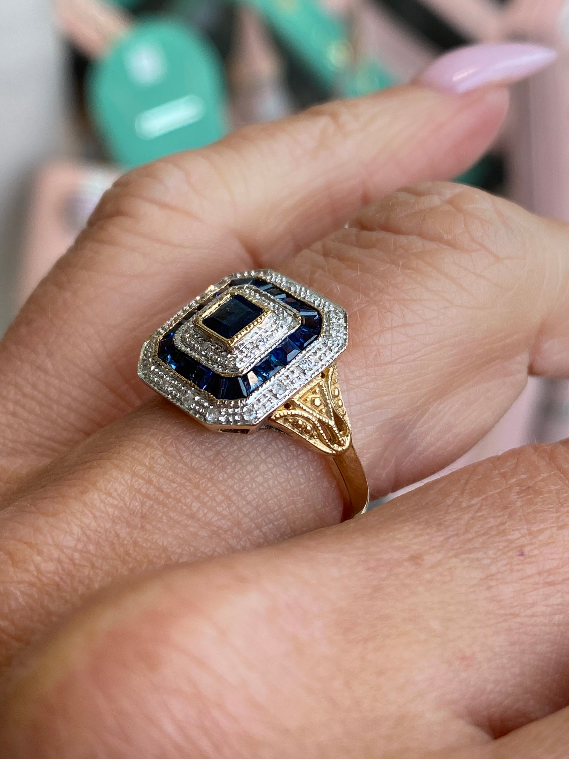 9ct gold sapphire and diamond ring by Luke Stockley featuring a central blue sapphire and sparkling diamonds in a detailed setting