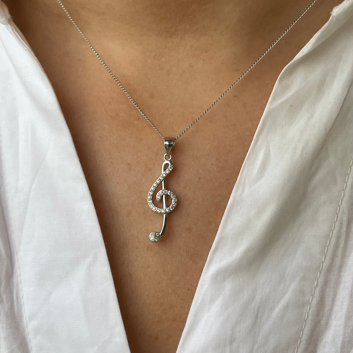 Silver CZ musical necklace featuring a treble clef pendant by Insignia, stylish jewelry accessory for music lovers.