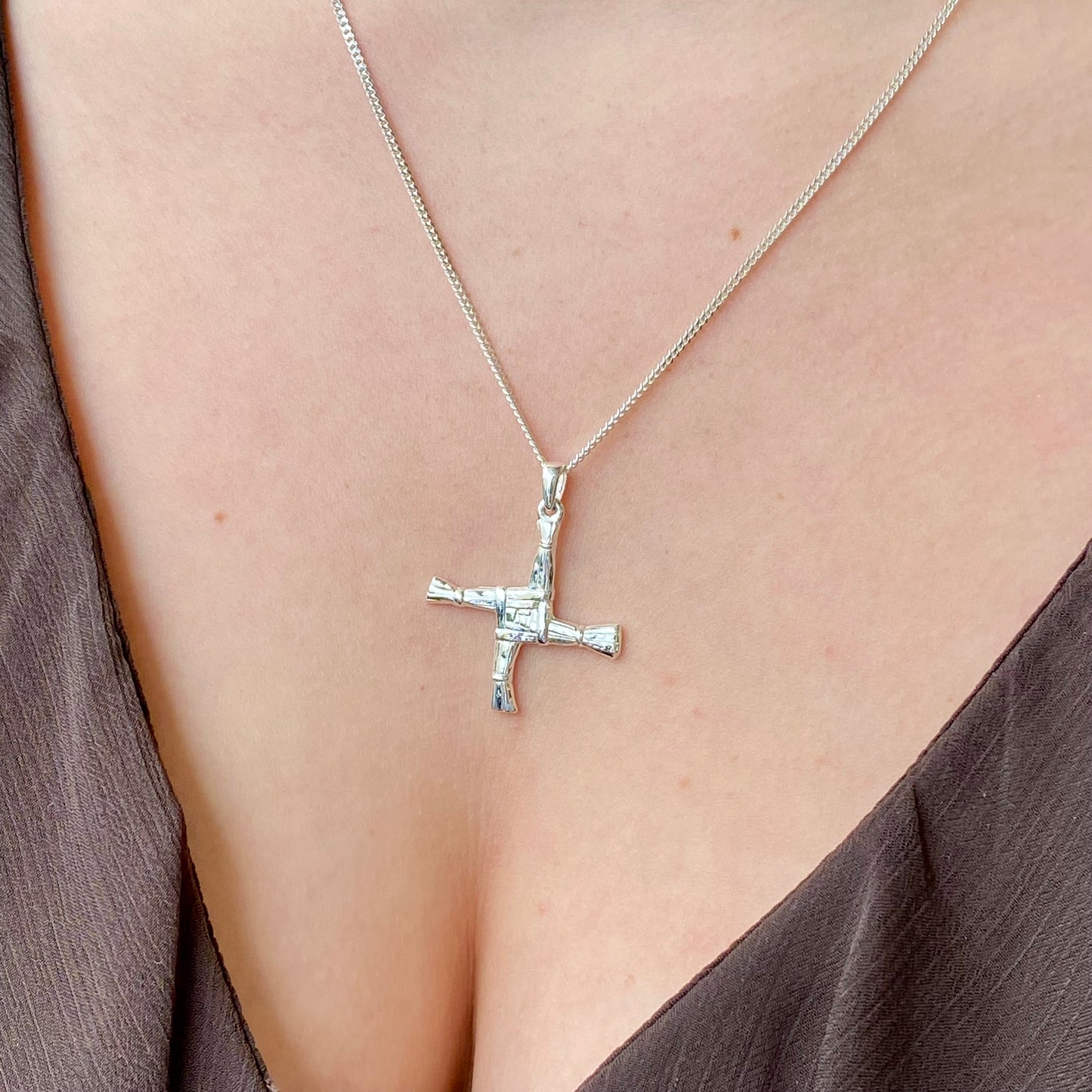 Large silver St Bridget cross necklace by Clandela, featuring intricate detailing and a shiny finish on a delicate chain.