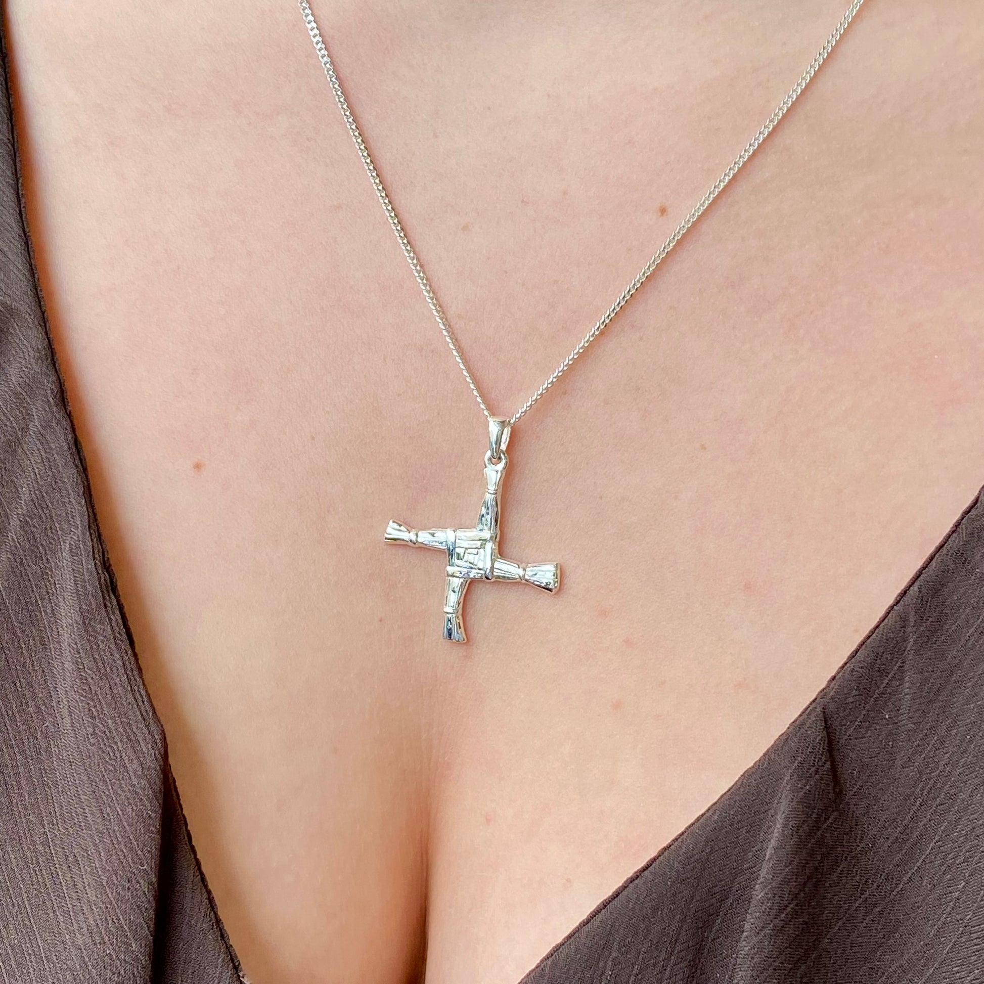 Large silver St Bridget cross necklace by Clandela, featuring intricate detailing and a shiny finish on a delicate chain.