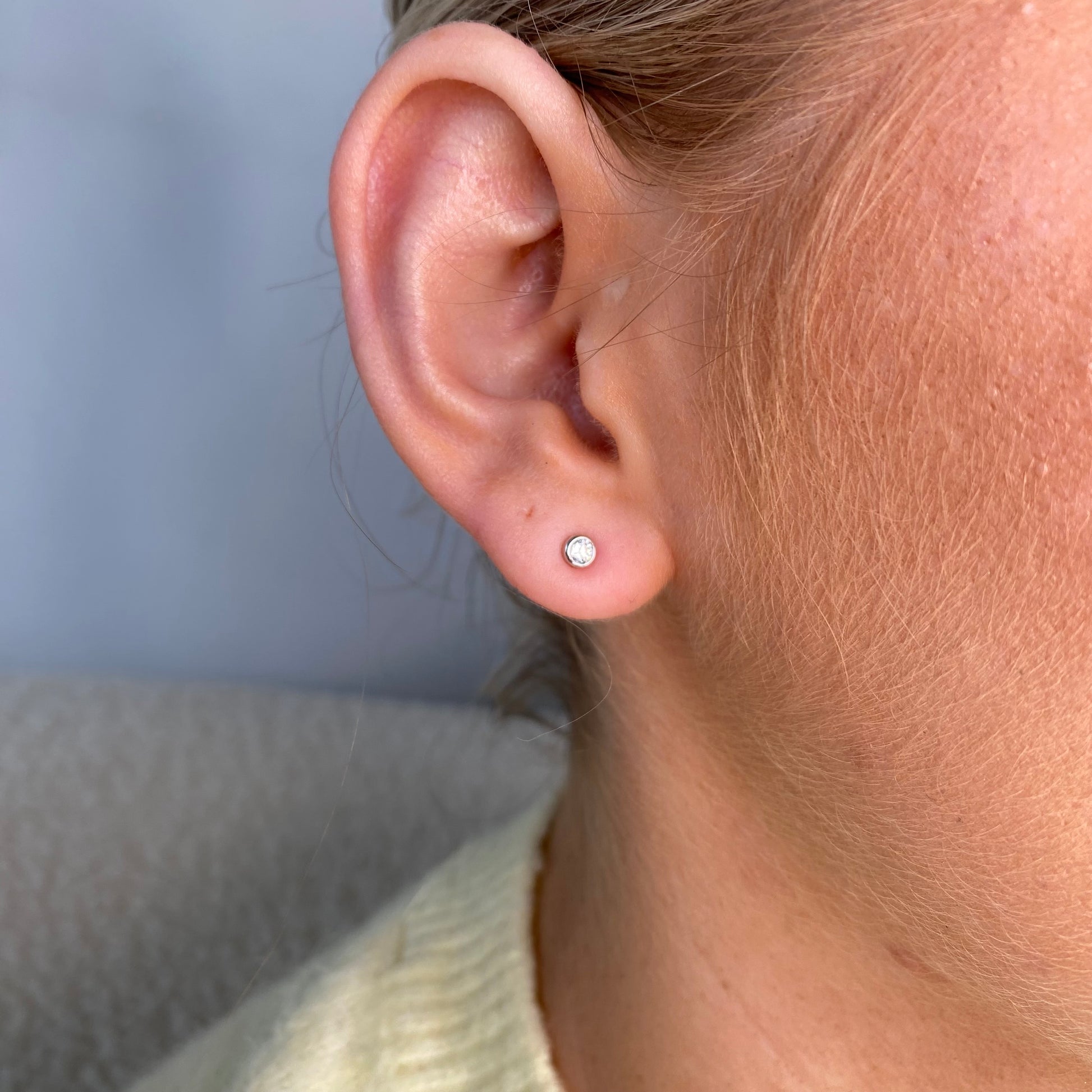 Silver 2mm CZ bezel set stud earrings for kids by Comero, featuring sparkling cubic zirconia stones on a classic stud design.